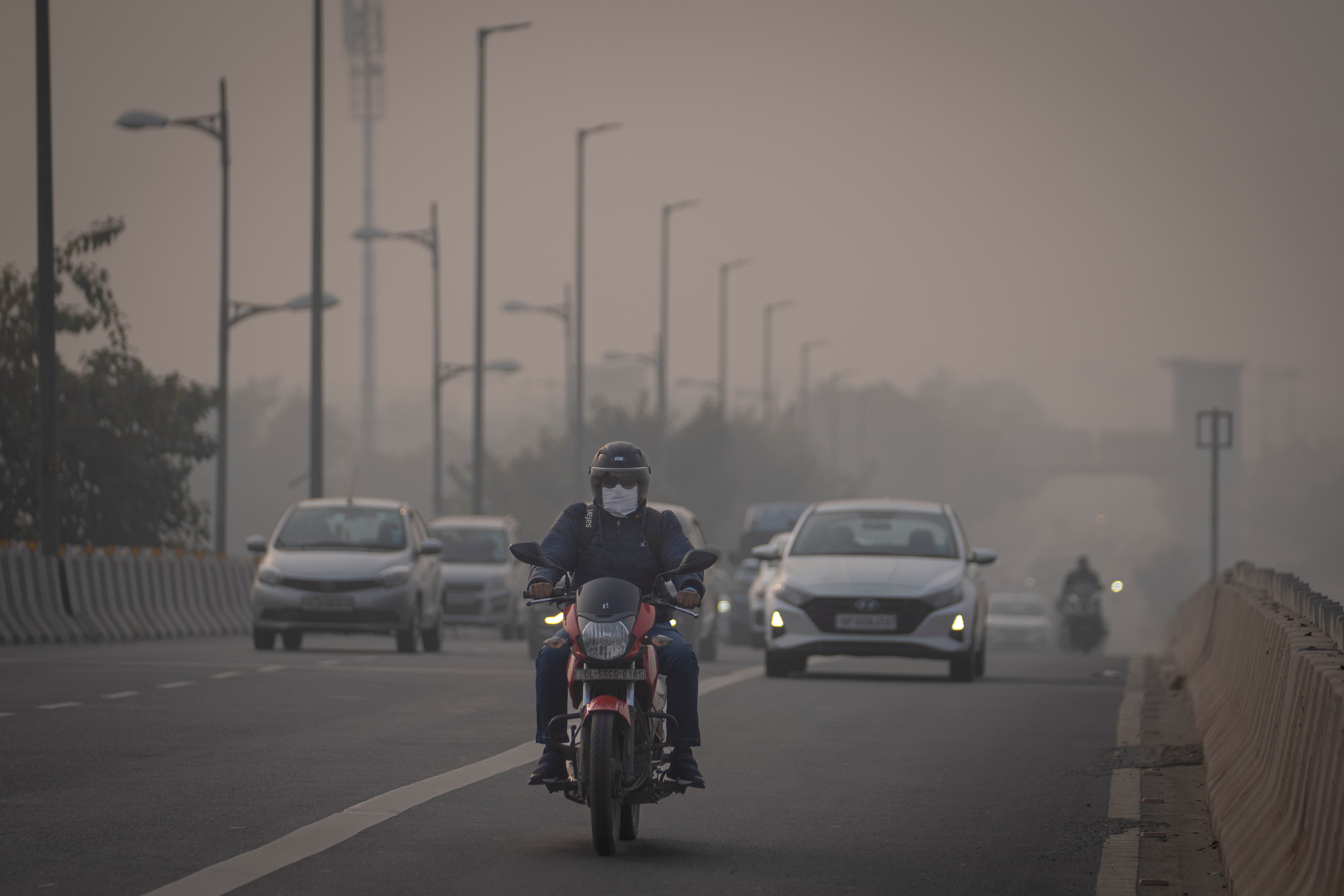 A motorcyclist drives wearing pollution mask amid smog in Delhi