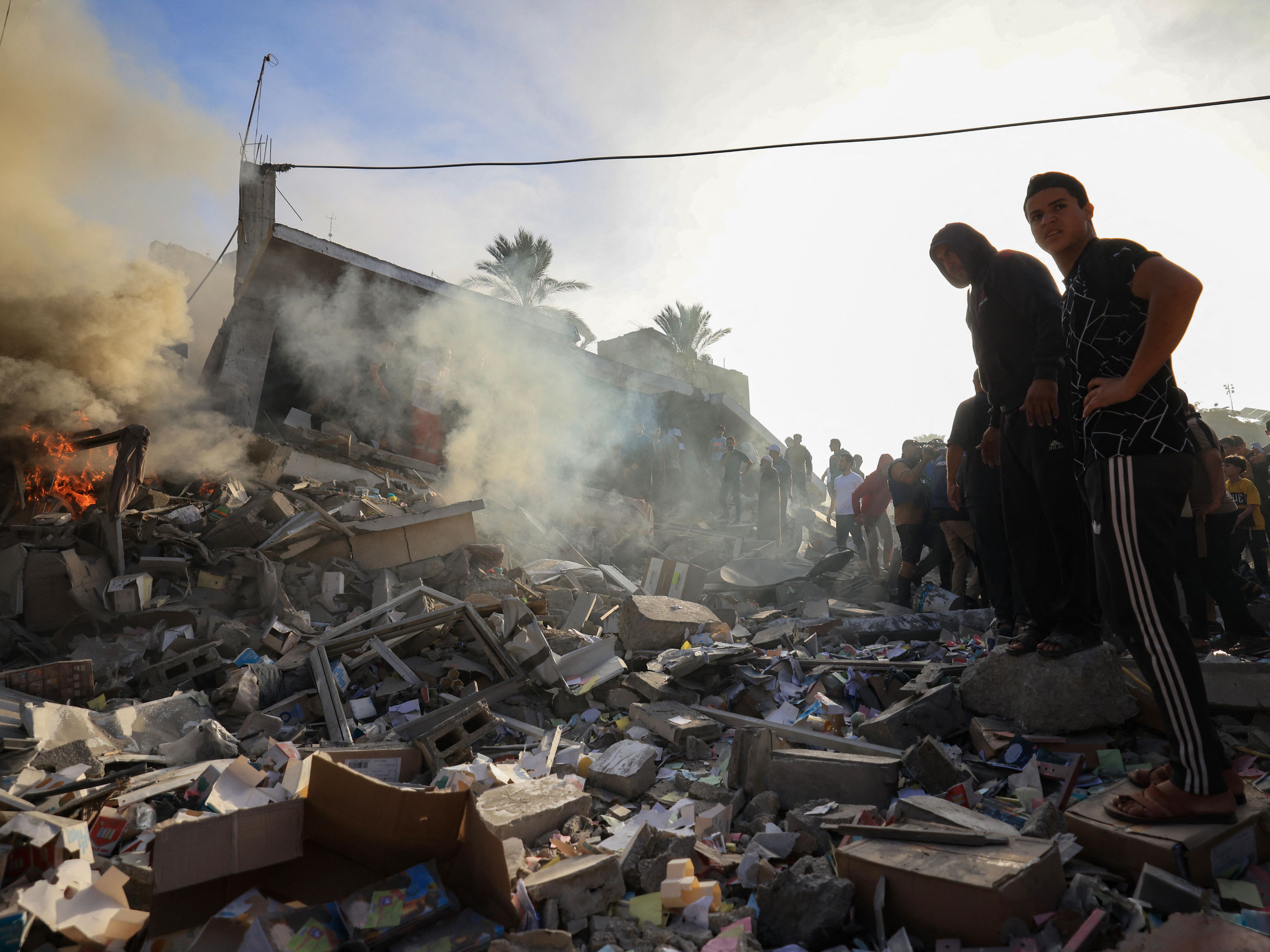 Palestinians stand above debris after Israeli bombardment in Khan Yunis in the southern Gaza Strip