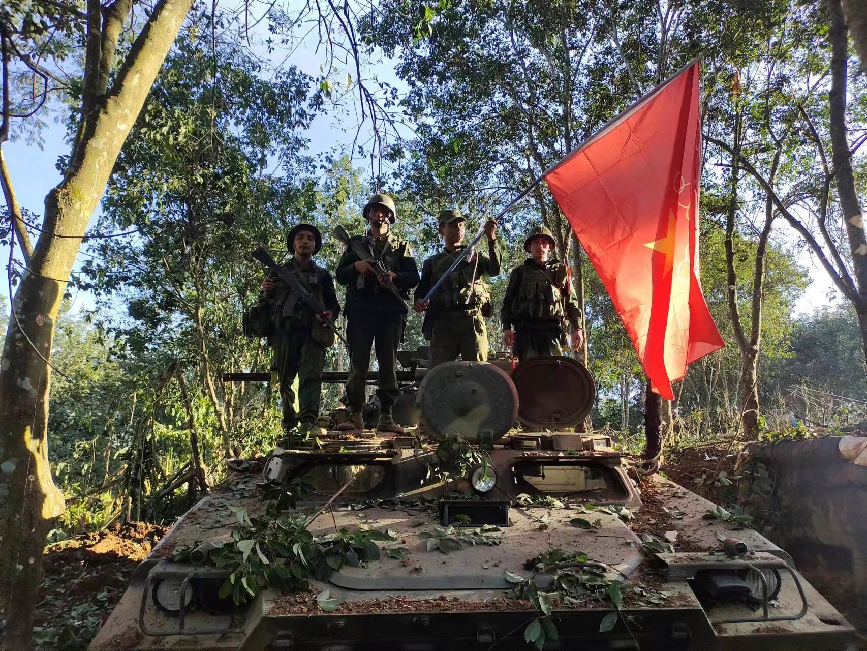 Members of the Myanmar National Democratic Alliance Army hold the group’s flag as they pose for a photograph on a captured army armored vehicle in Myanmar