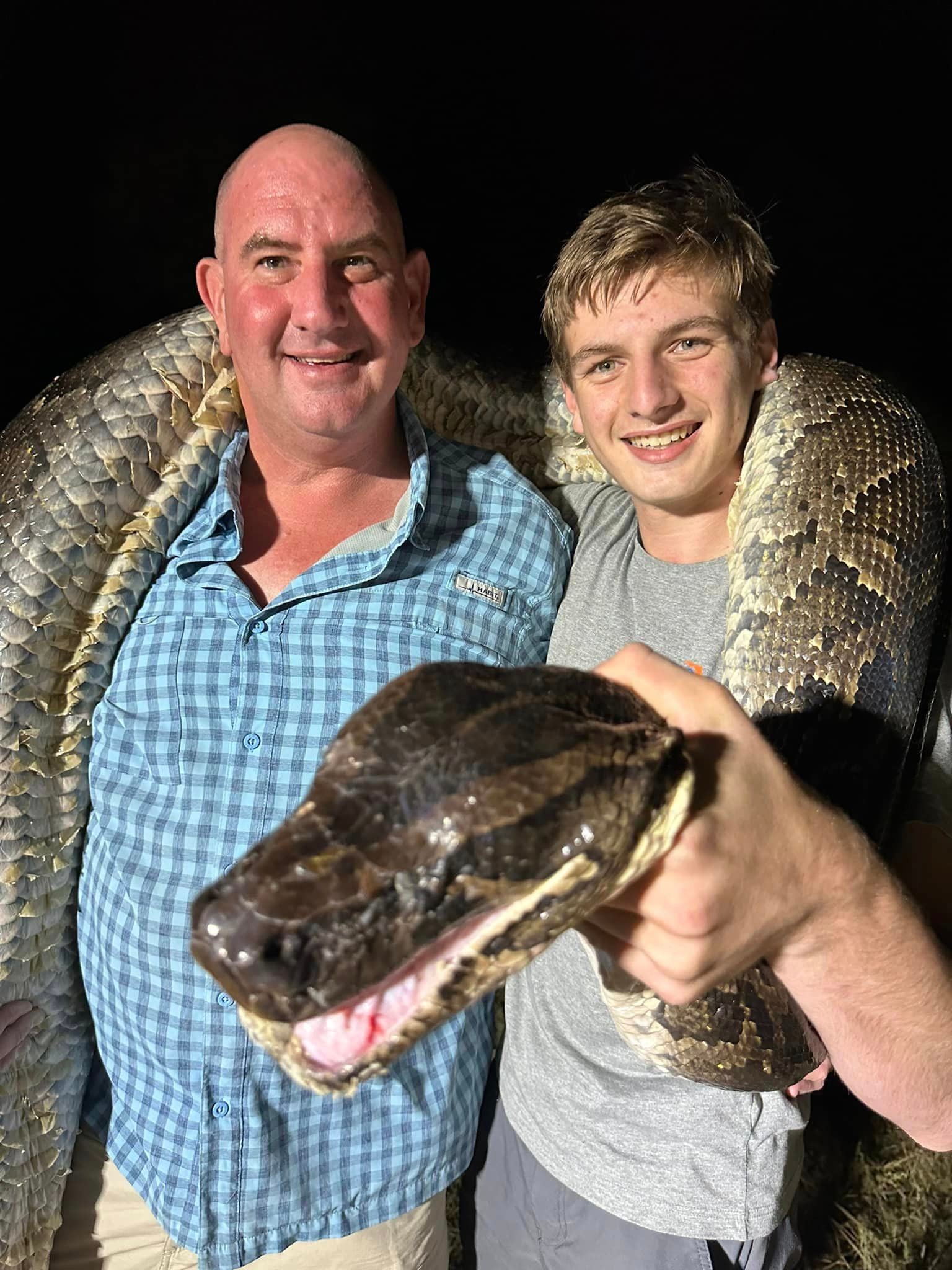 Father and son Mike and Cole pose for a pic with the giant python they just wrangled