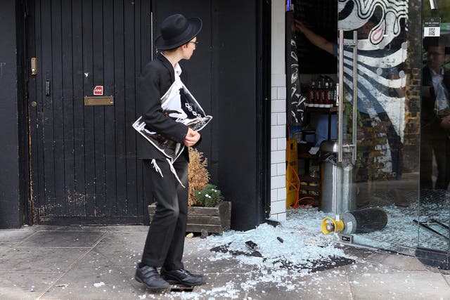 <p>A man looks at a vandalised kosher restaurant in Golders Green, London, near a bridge with ‘Free Palestine’ painted on it</p>