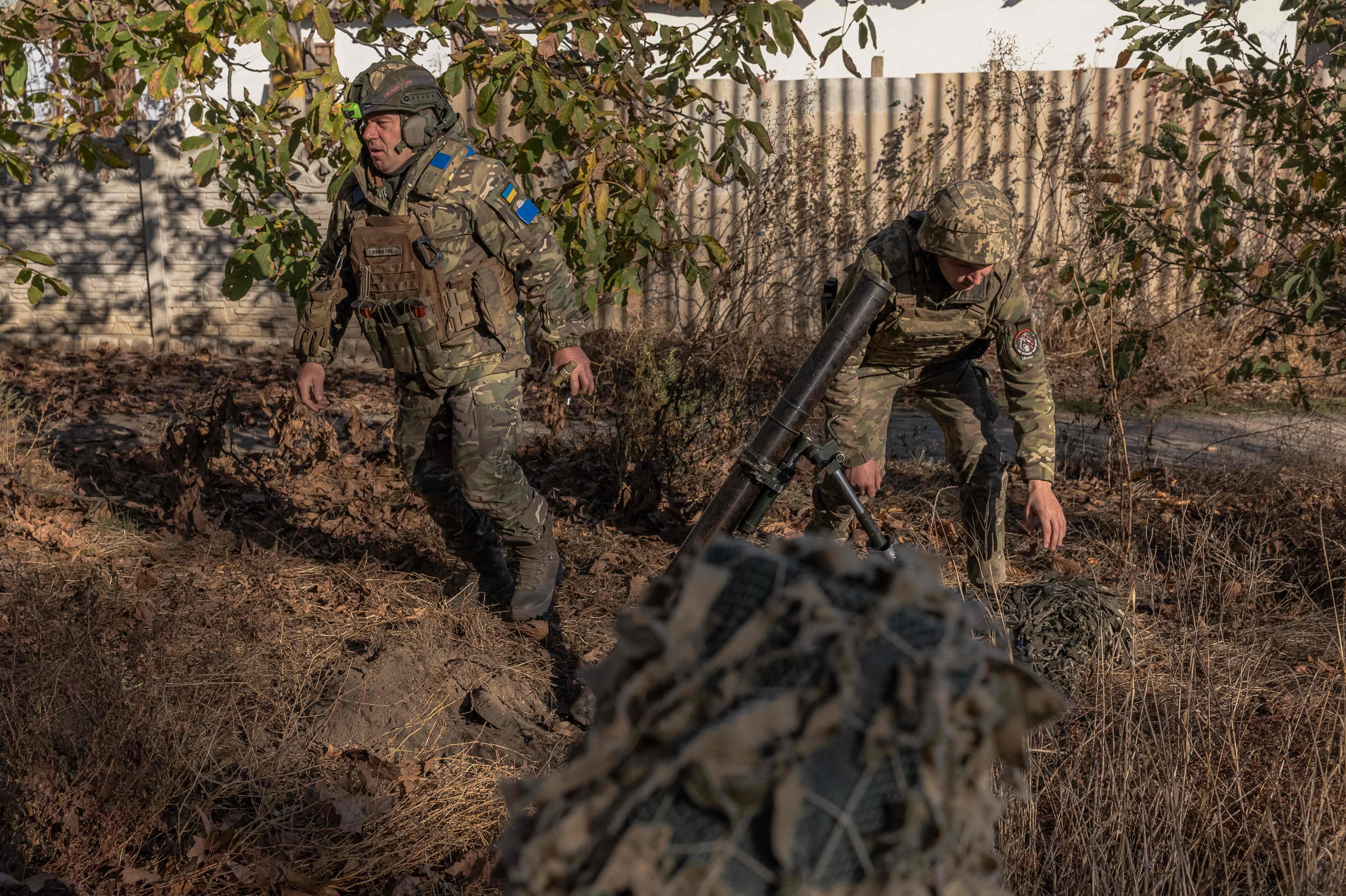 Ukrainian servicemen of the 123rd Territorial Defense Brigade in action while firing a mortar over the Dnipro River toward Russian positions