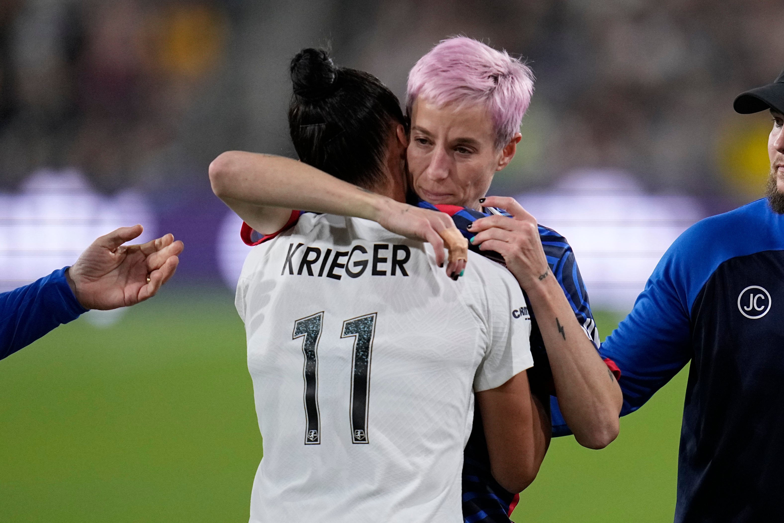 Rapinoe, right, embraces Ali Krieger as she comes off the field after suffering an achilles injury in her final game