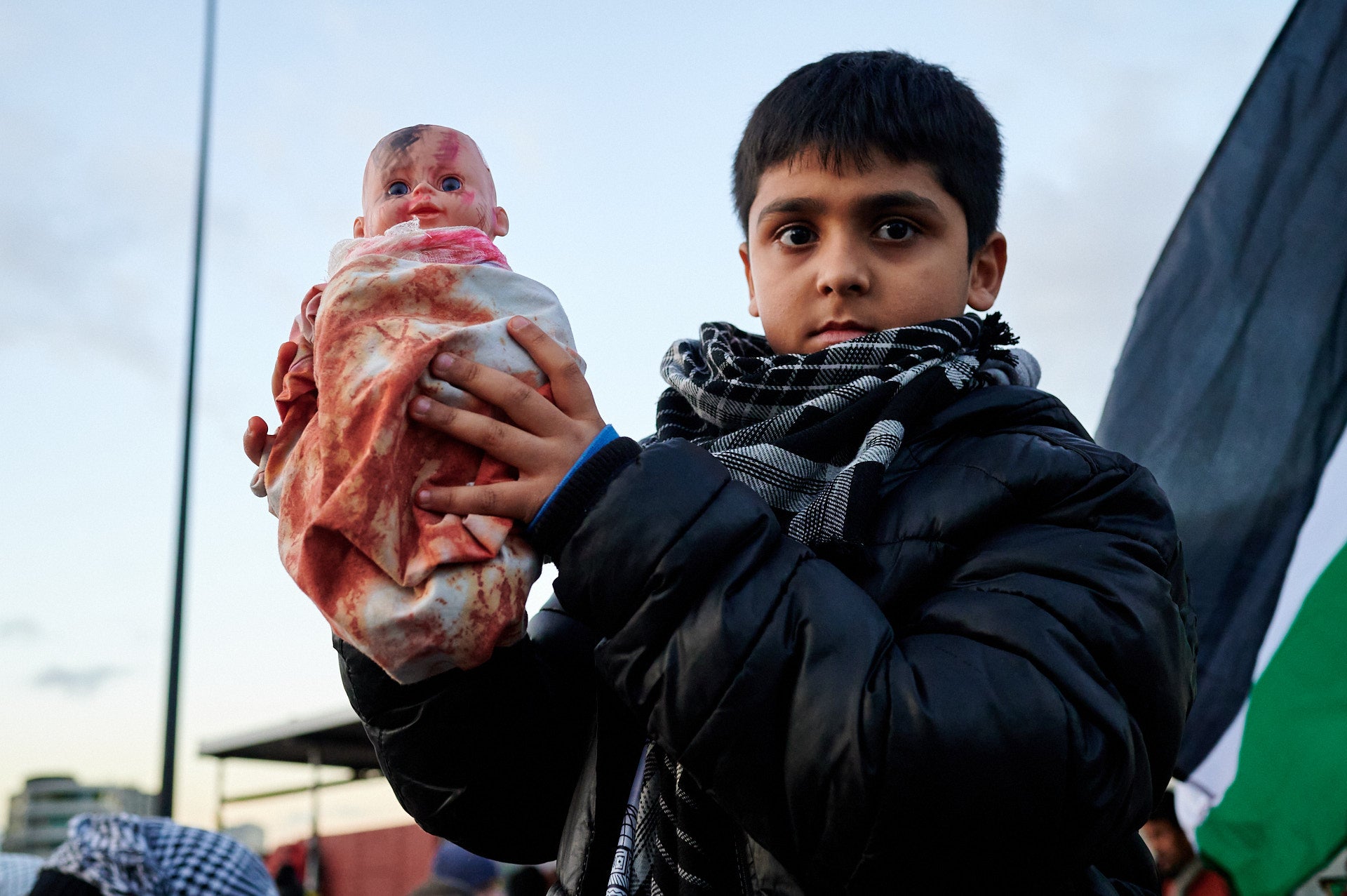 A young boy holds up a doll as a protest symbol on Vauxhall Bridge
