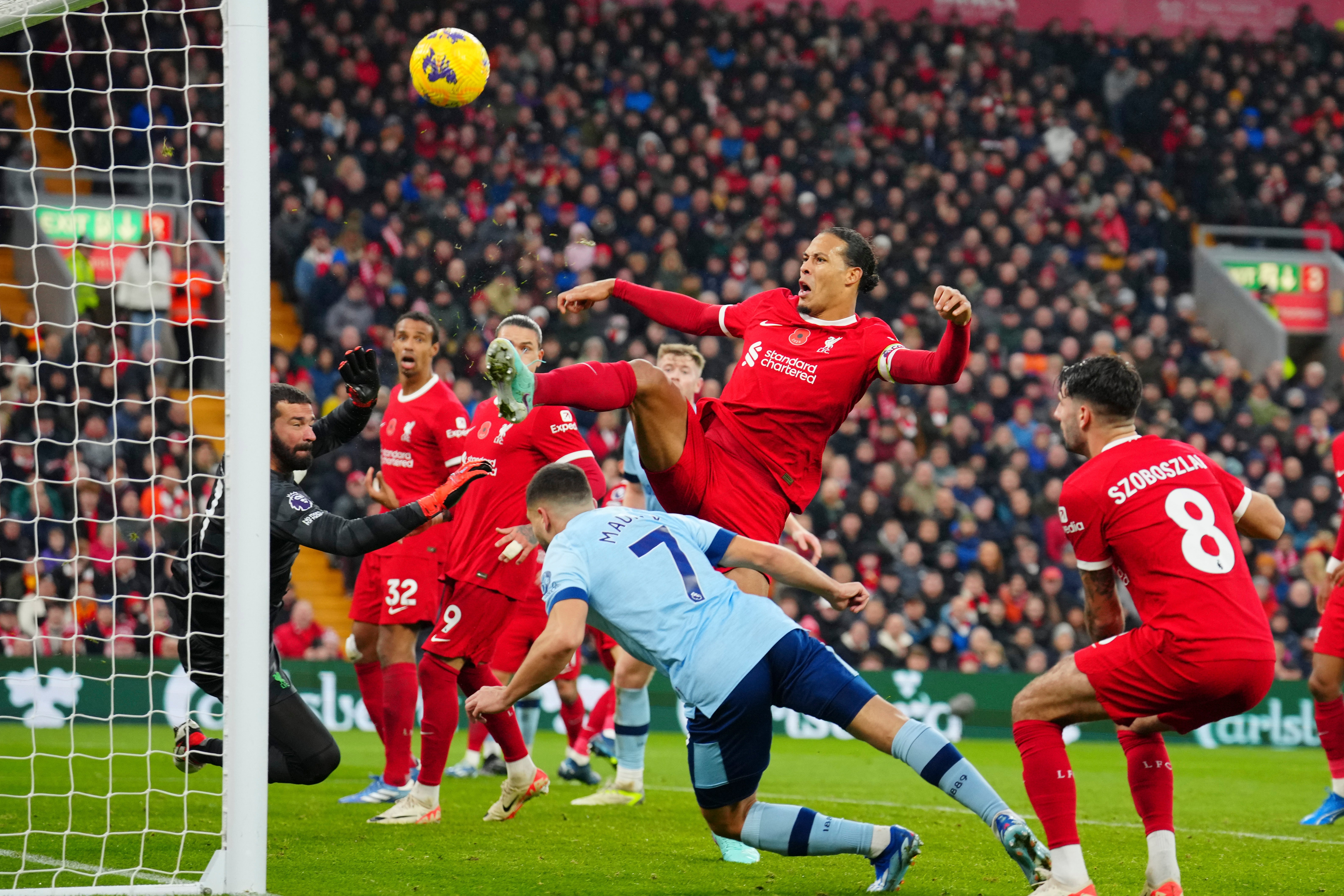 Virgil van Dijk, top, and goalkeeper Alisson block a header by Neal Maupay