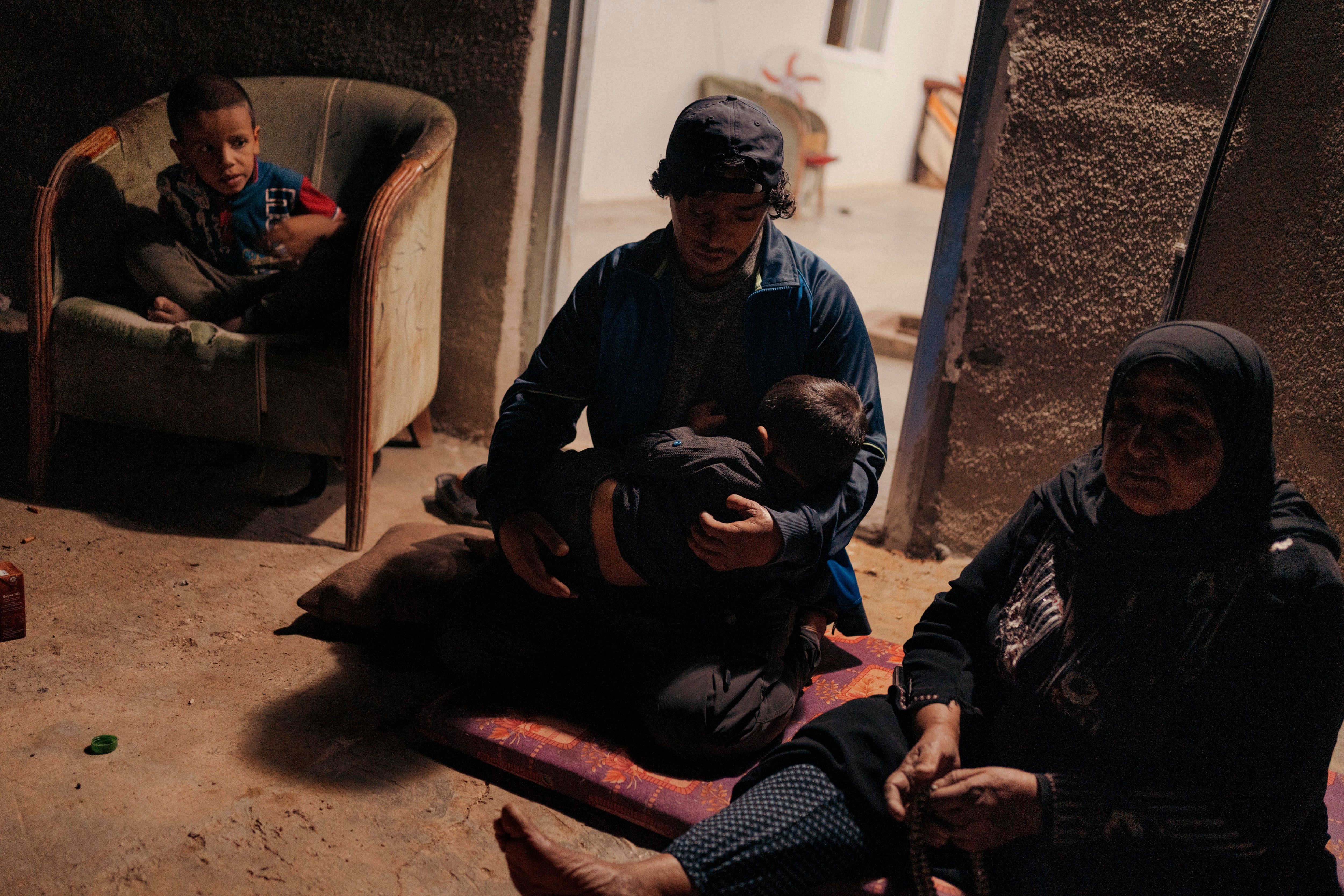 Awdah Hathaleen, an English teacher and activist from Umm al-Kheir, holds his son Watan in front of his house