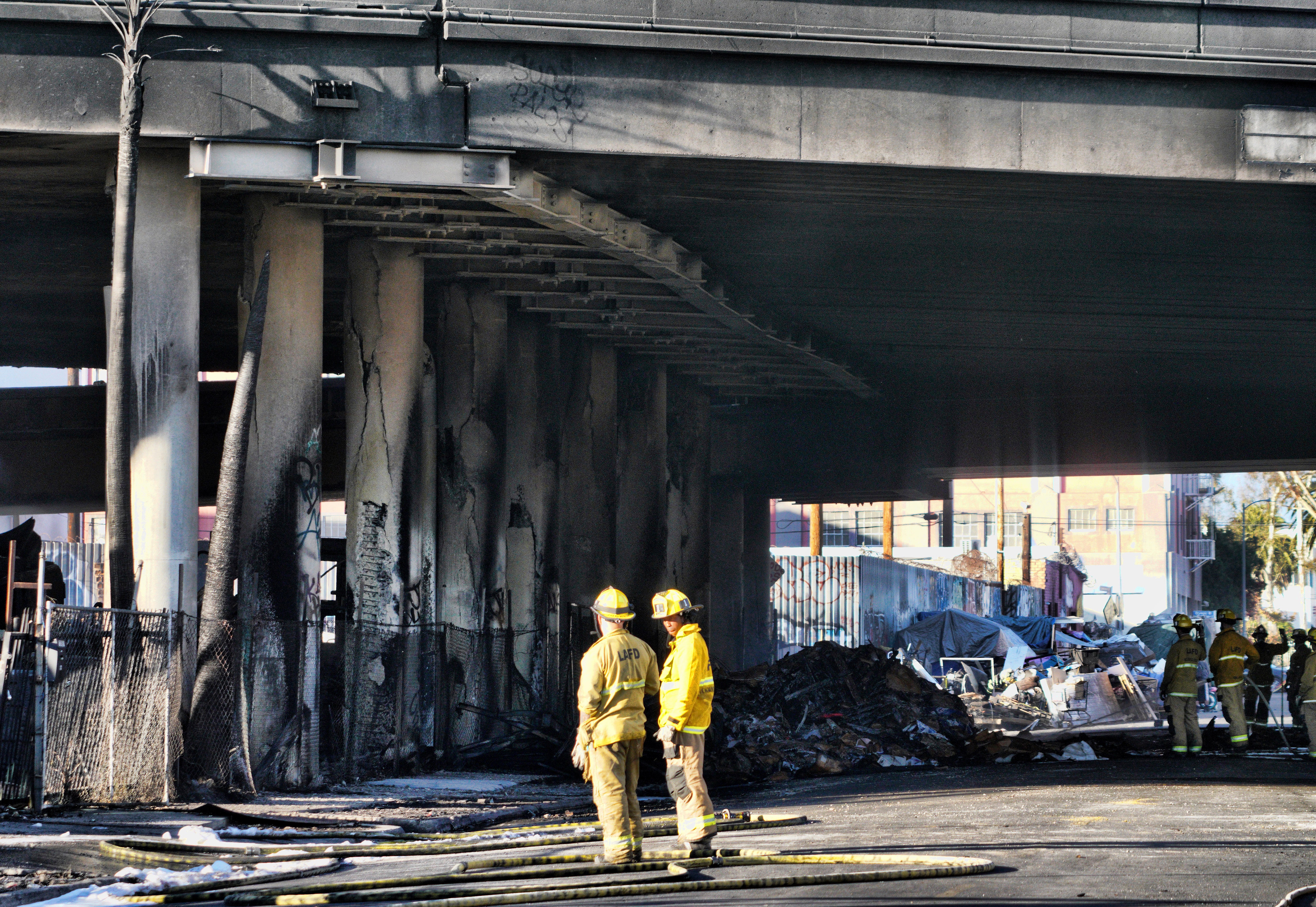 Firefighters assess the damage from a intense fire under Interstate 10 that severely damaged the overpass in an industrial zone near downtown Los Angeles