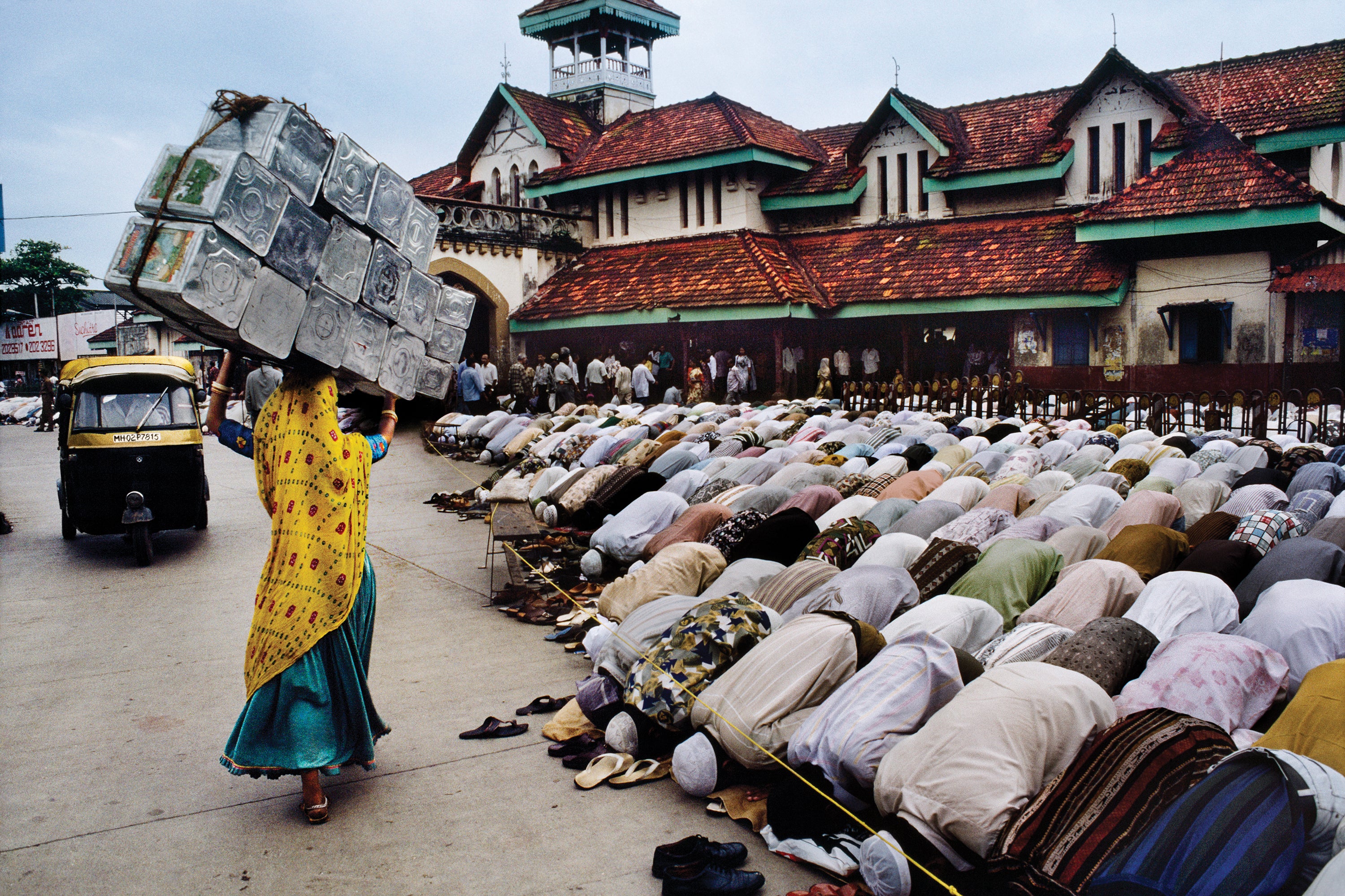 A woman passes men in prayer in Mumbai, India