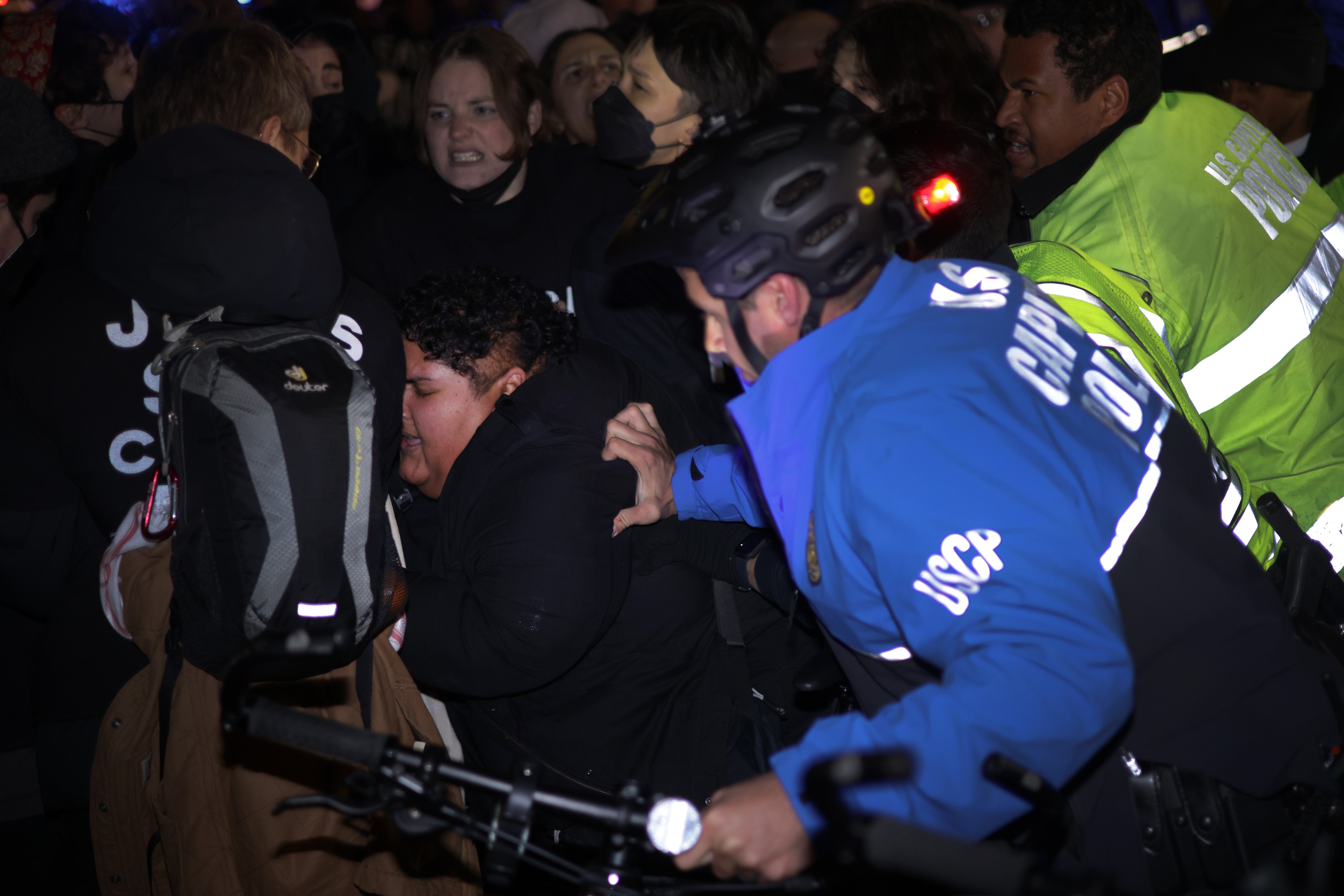 Members of U.S. Capitol Police try to push protesters away from the headquarters of the Democratic National Committee