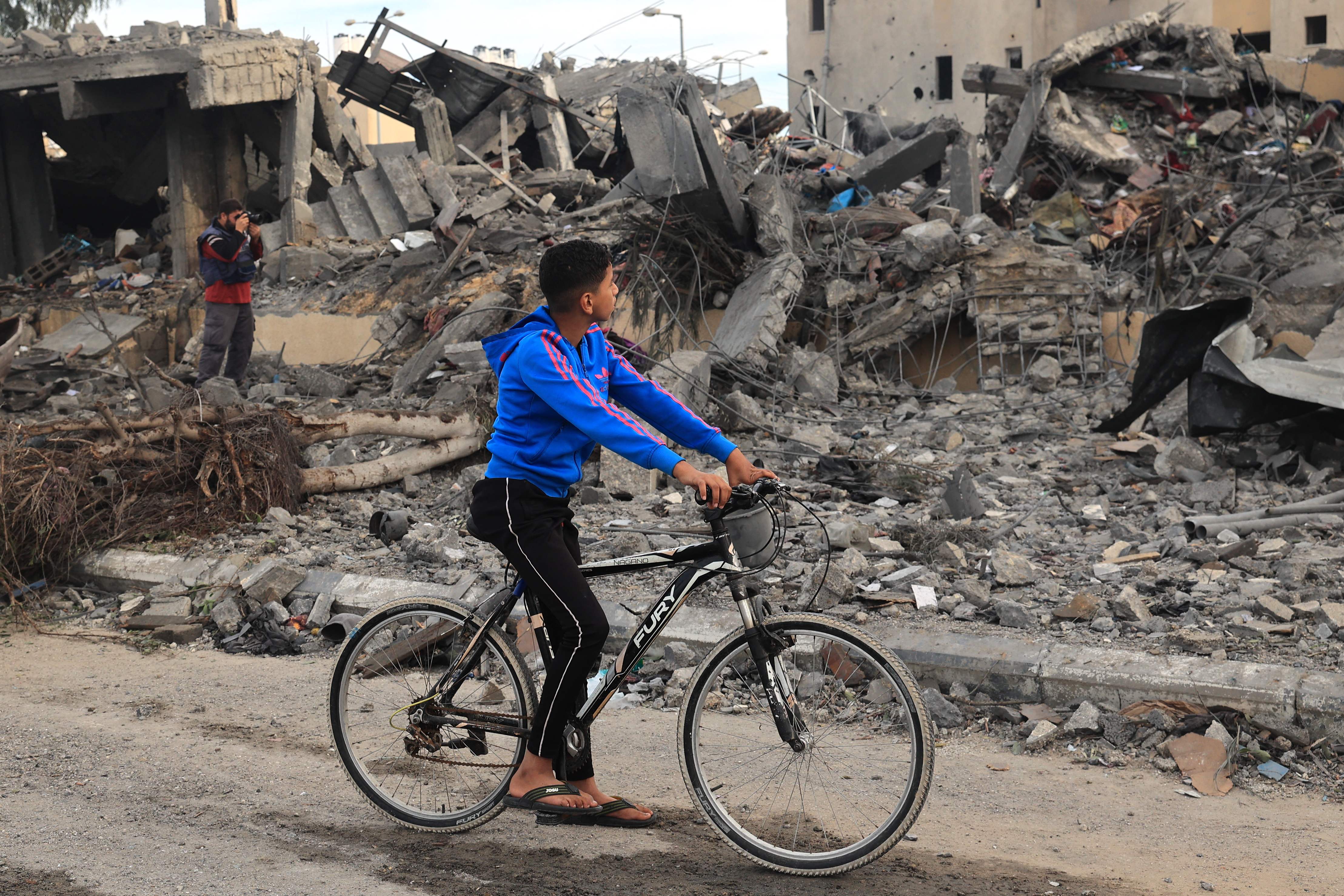 A Palestinian boy on a bicycle looks at rubble of a building following Israeli strikes in Rafah on Wednesday