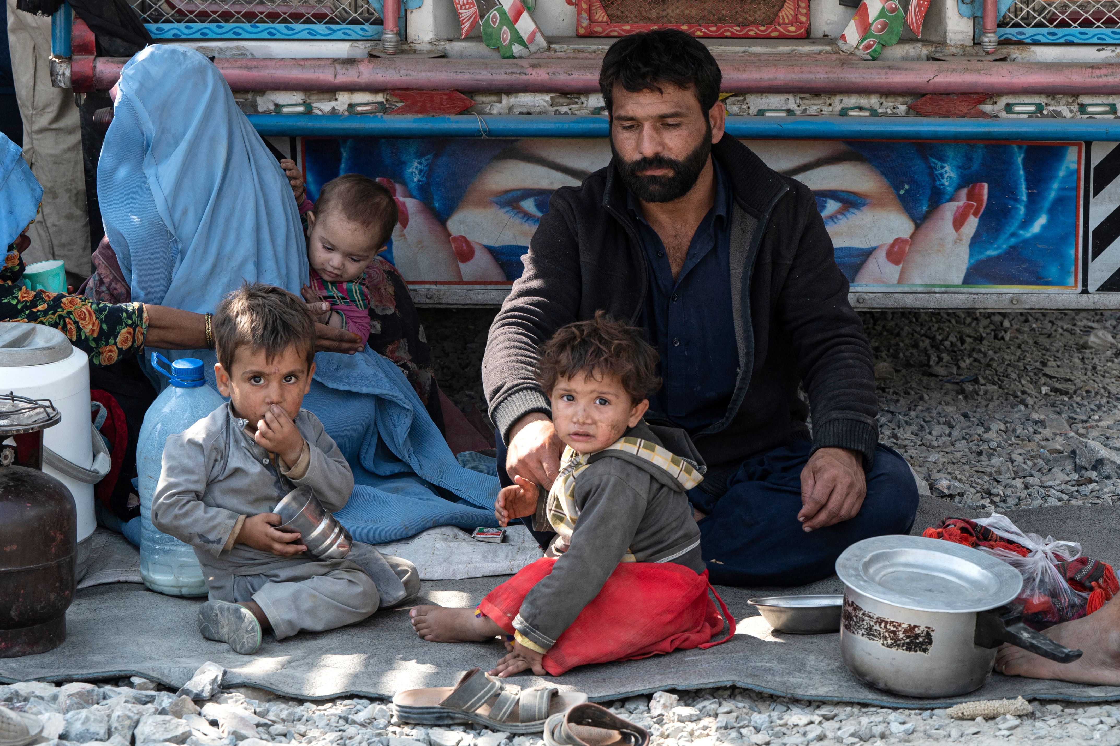 Afghan refugees sit beside a truck after their arrival from Pakistan