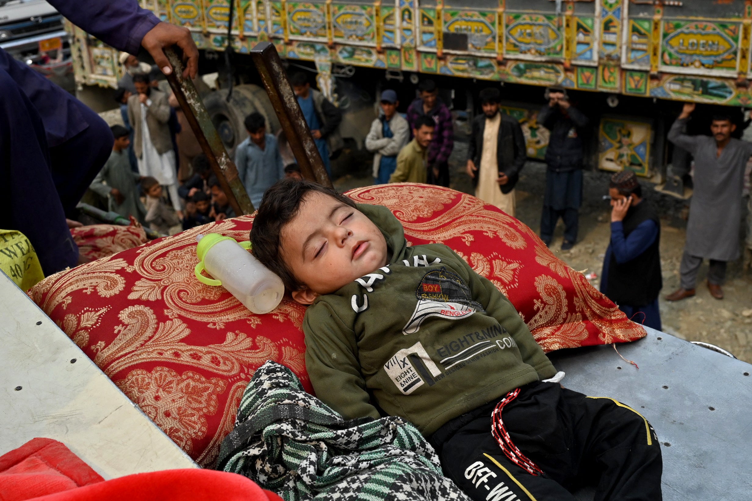 An Afghan child refugee sleeps above a truck as he arrives at the border