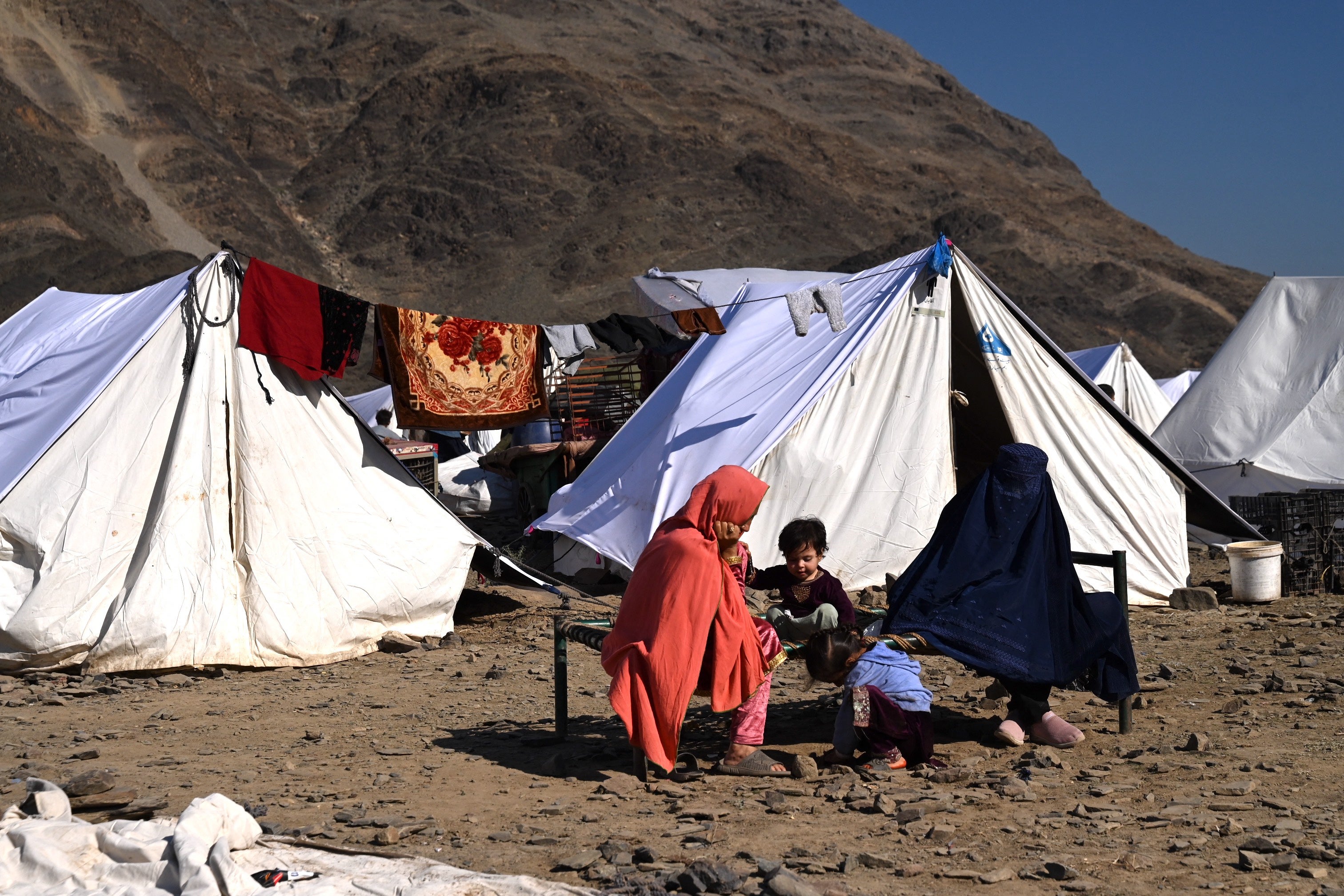 Afghan refugees sit outside their tents at a makeshift camp