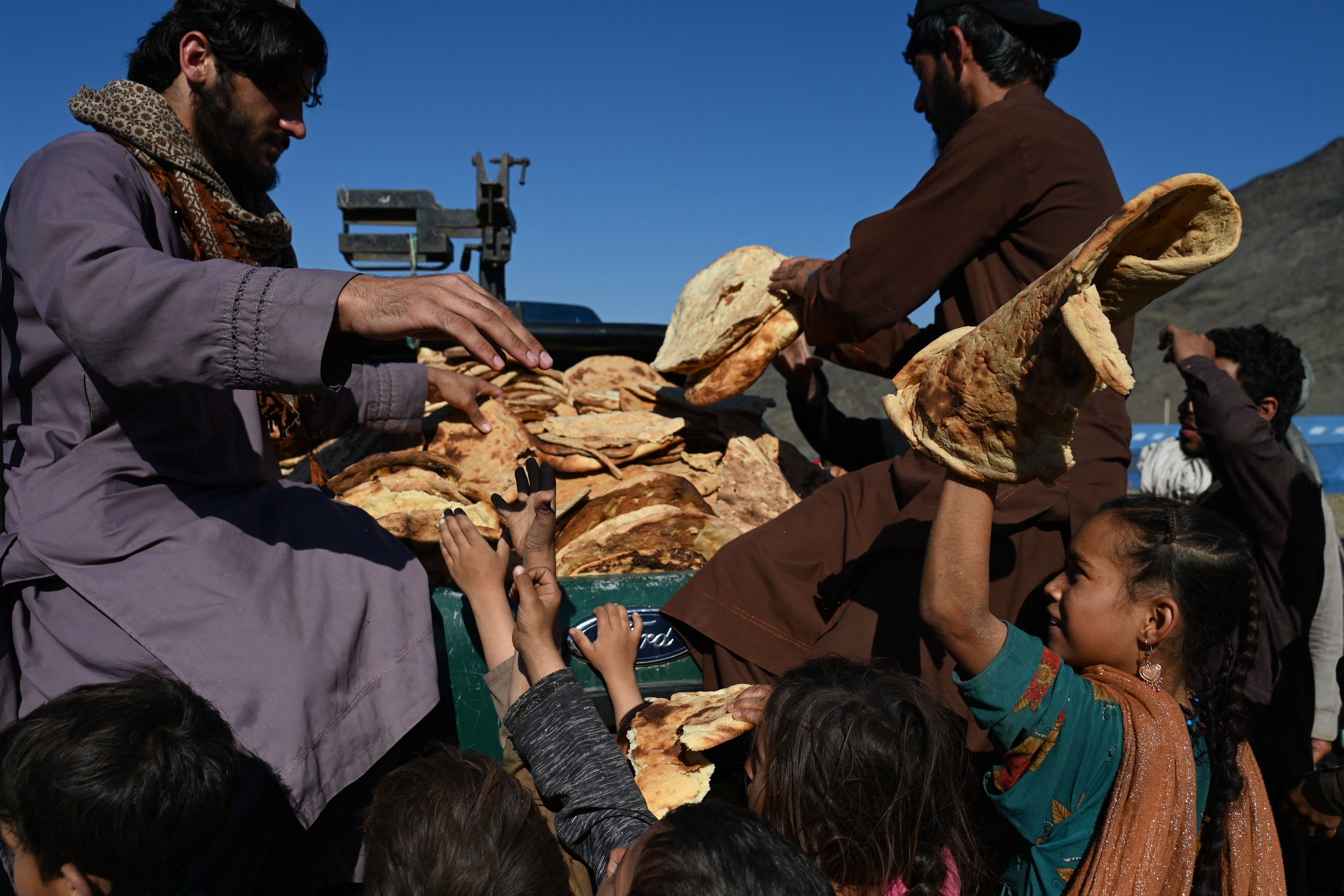 Afghan refugees’ children receive bread from a local charity