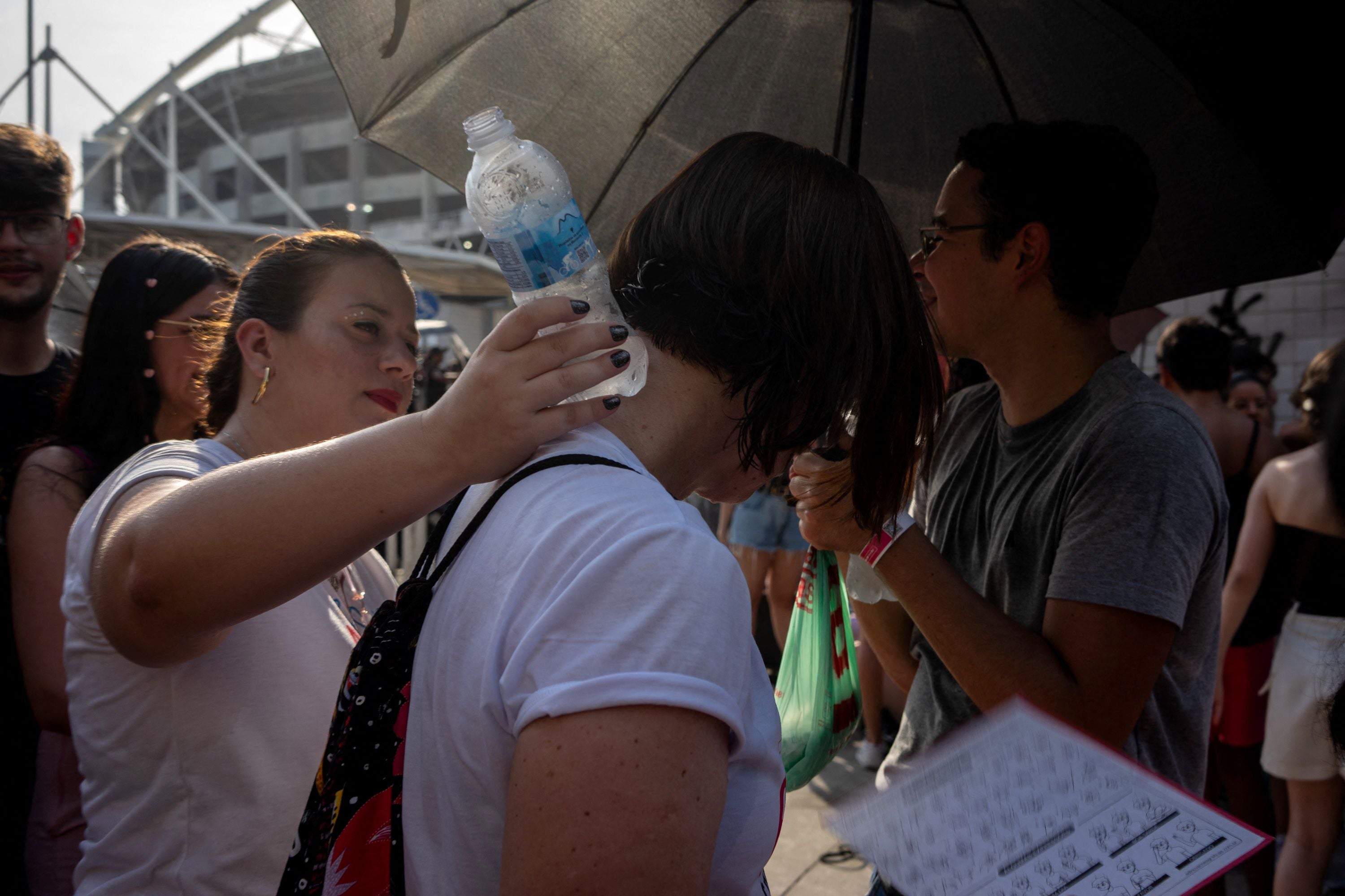 An Eras Tour concertgoer on 18 November helps another attendee cool down by placing a water bottle against the back of their neck