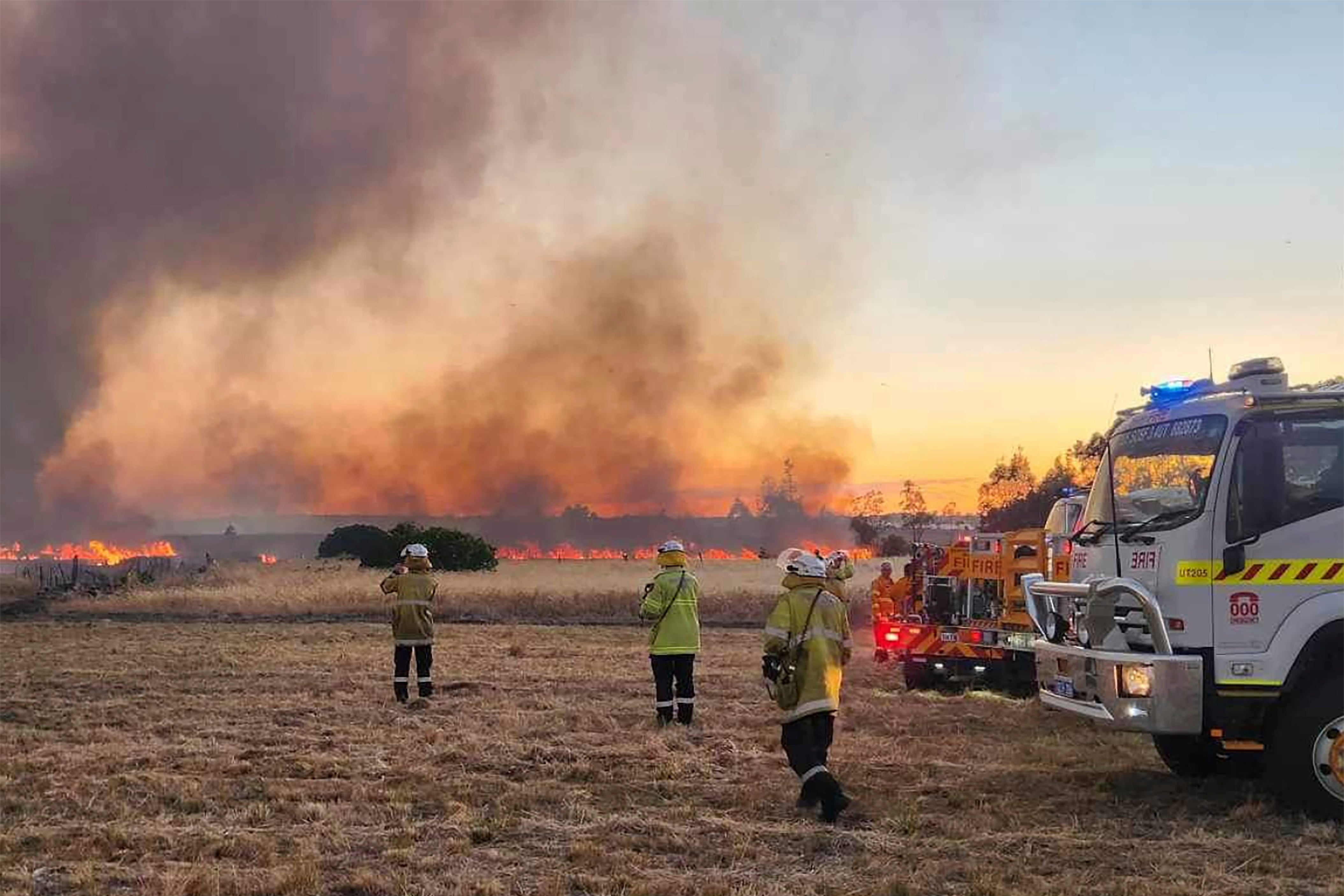 West Australian firefighters watch as grassland burns near the city of Wannaroo, north of Perth