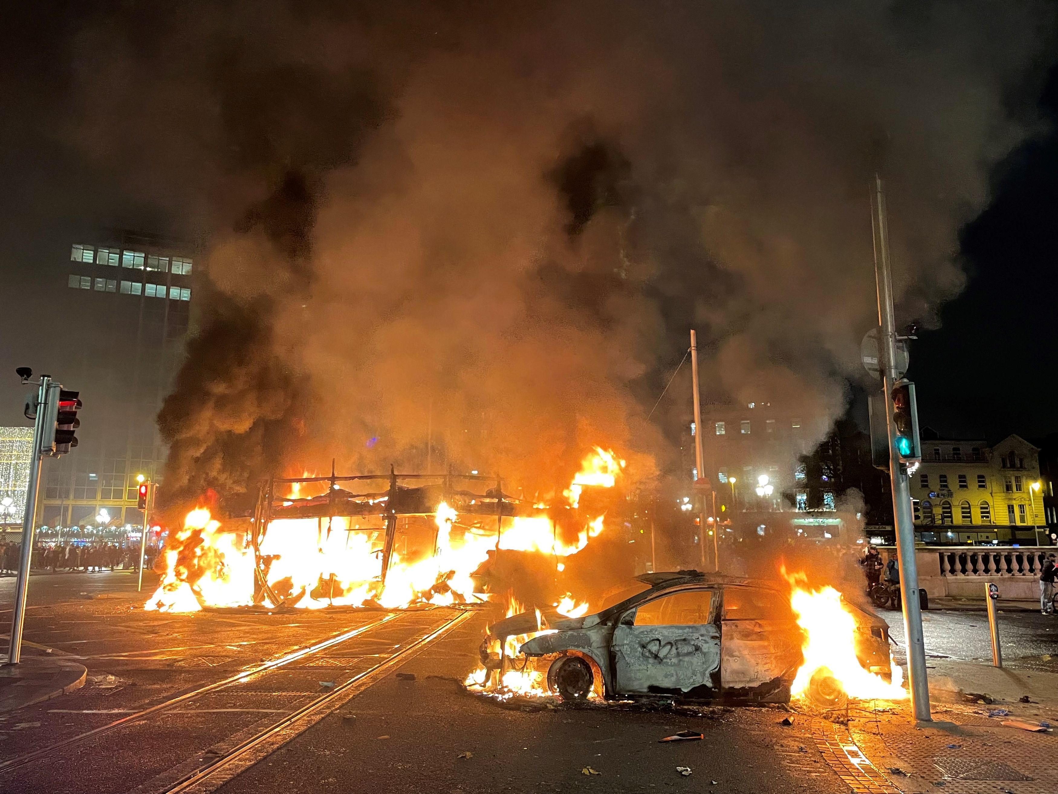 A bus and car on fire in Dublin’s city centre after violent protests erupted following a stabbing attack