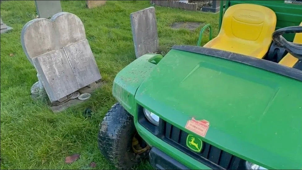 A small vehicle appearing to be parked next to two headstones at the Gloucestershire cemetery