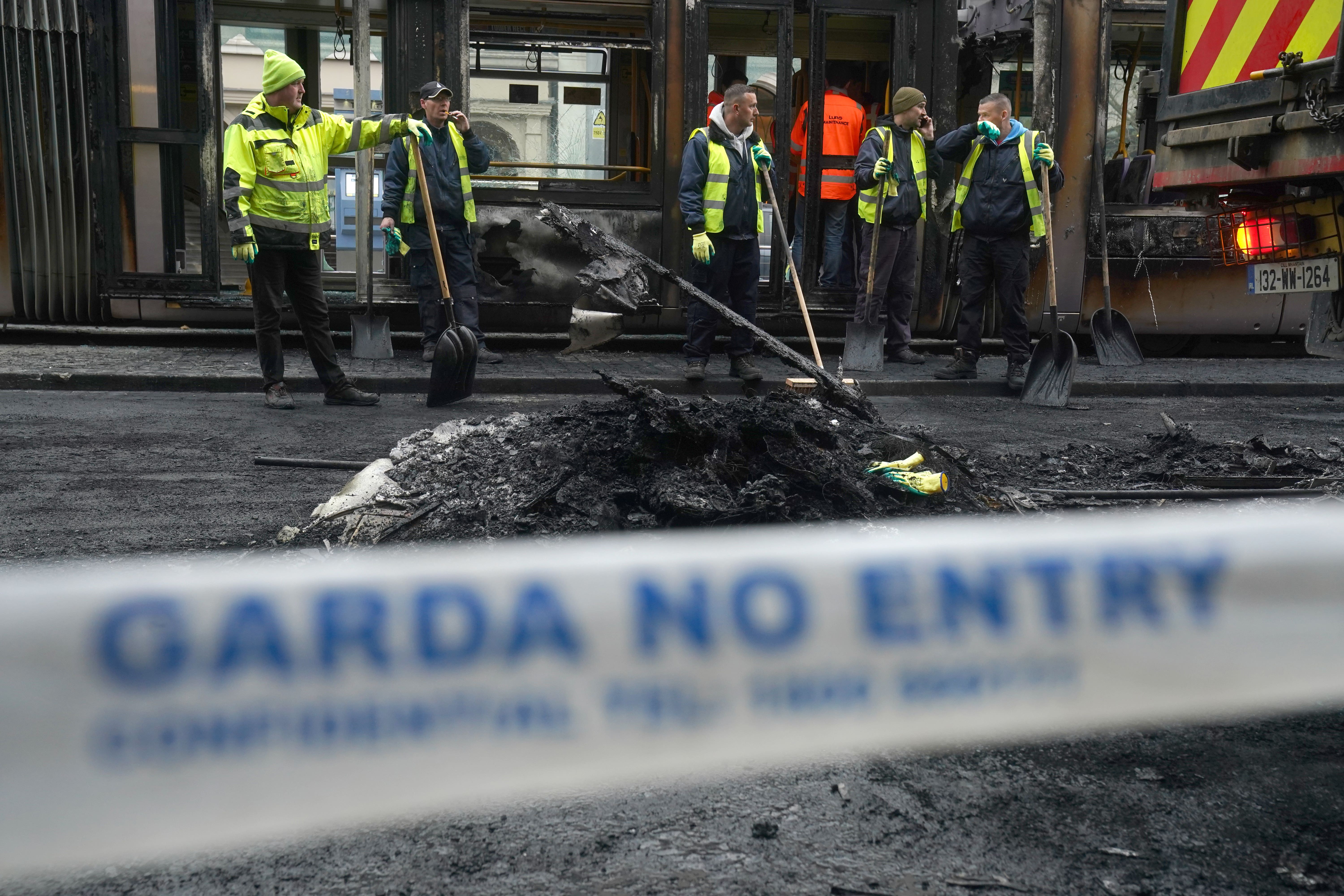 Debris is cleared from a burned out Luas and bus on O’Connell Street in Dublin, in the aftermath of violent scenes in the city centre on Thursday evening (Brian Lawless/PA)