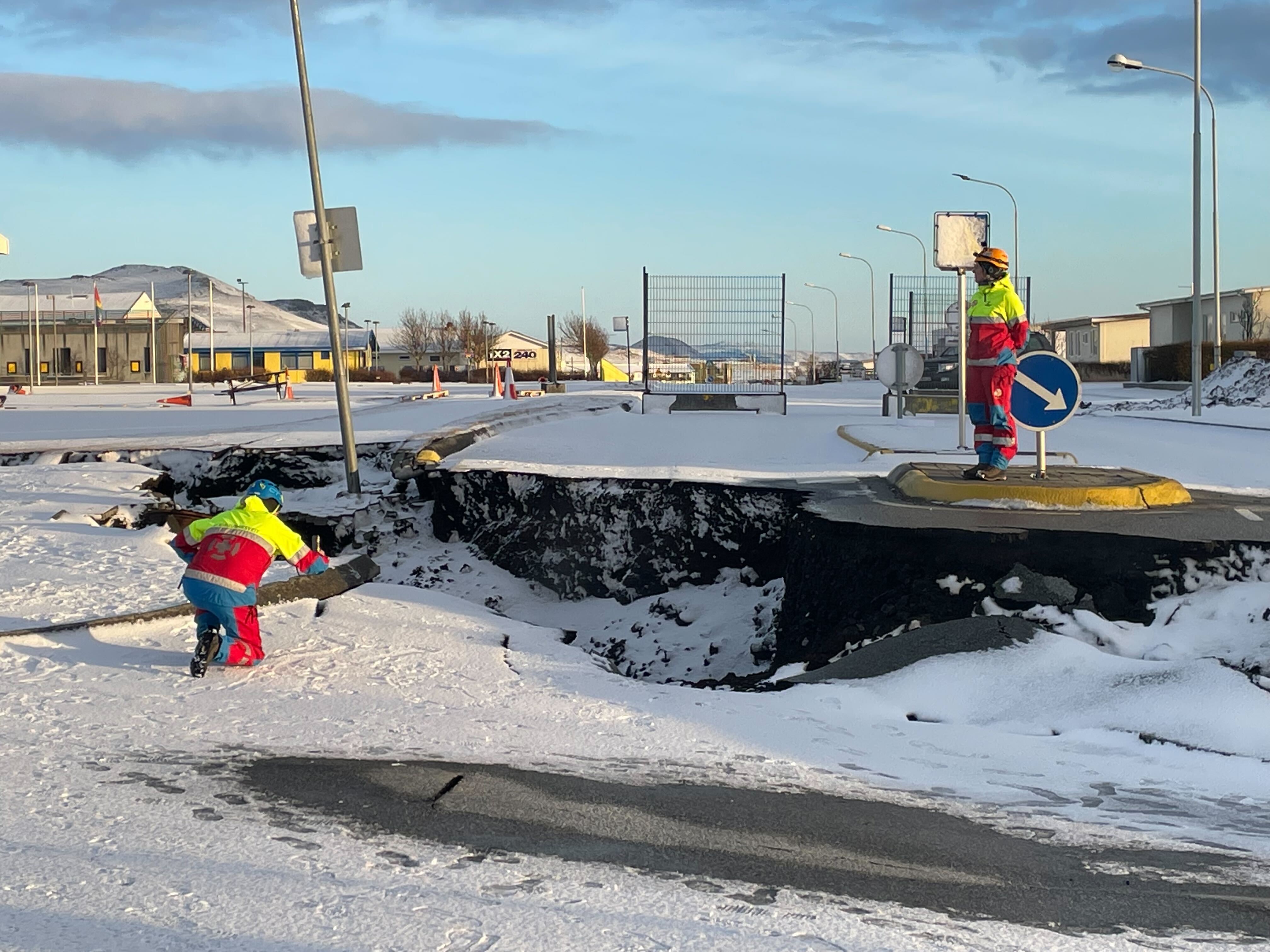 Rescue workers pose by a yawning chasm in Grindavík