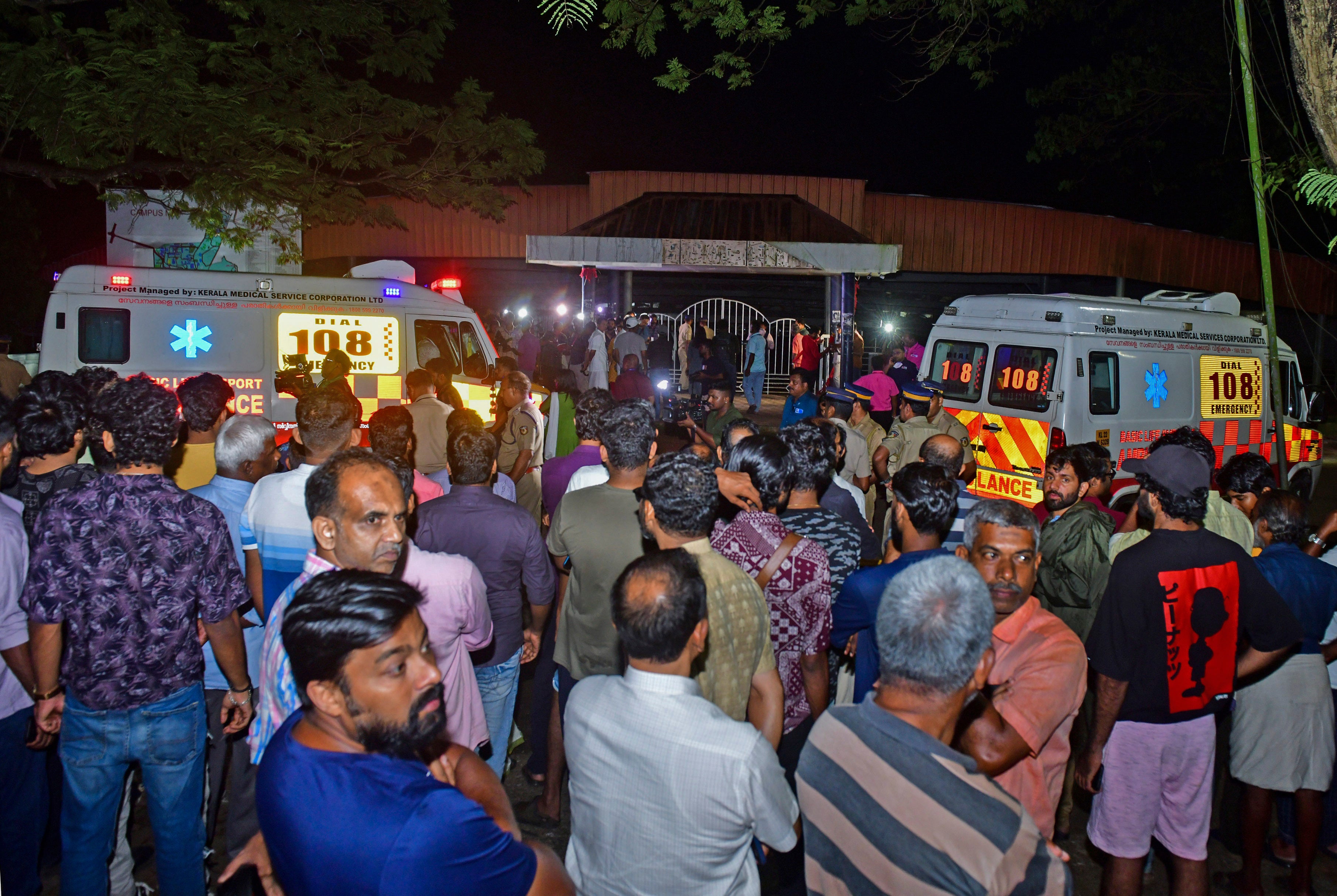 People gather outside after a stampede at the venue of a music concert at the Cochin University