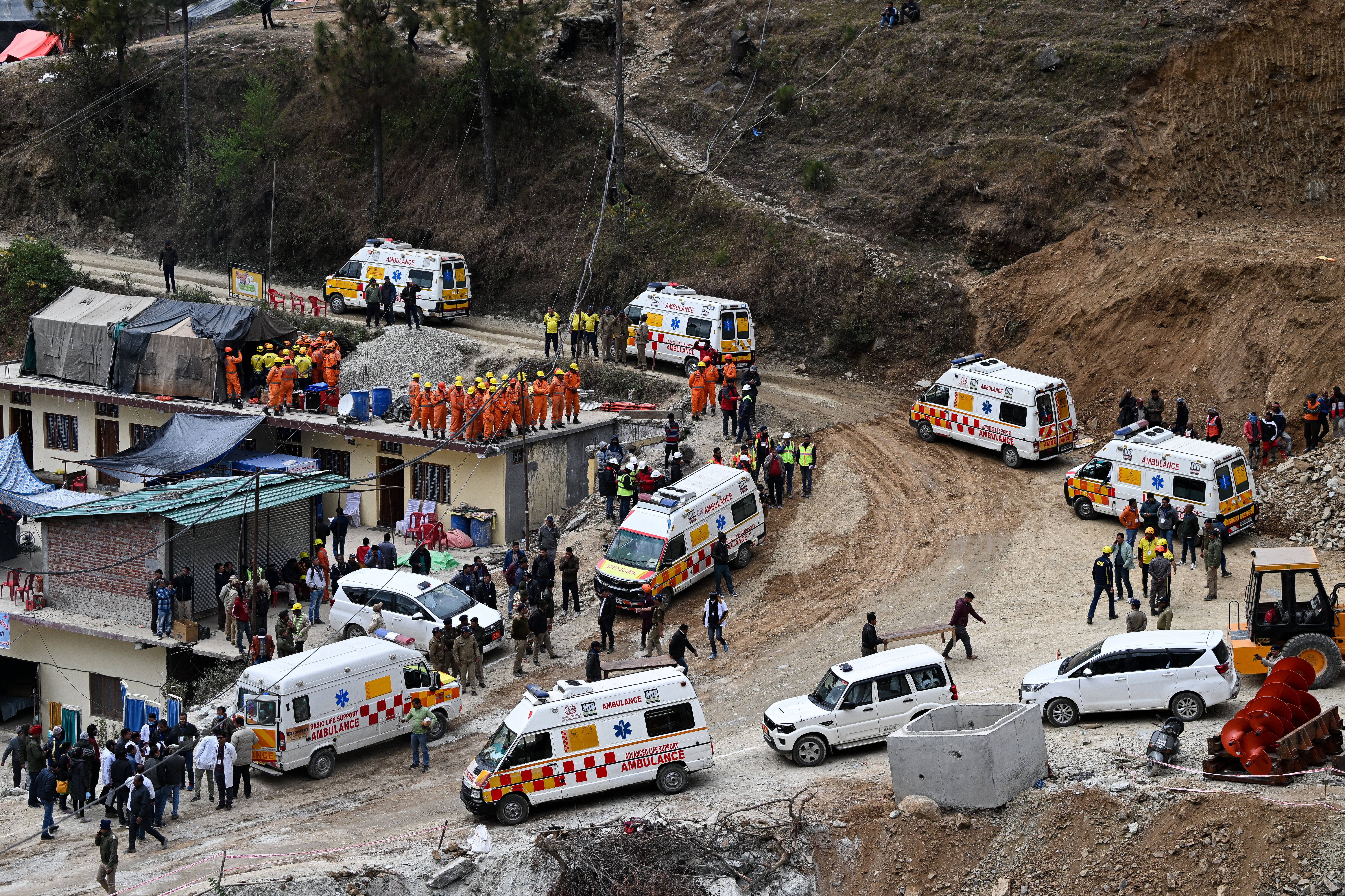 Ambulance and emergency vehicles are on standby near the face of the collapse