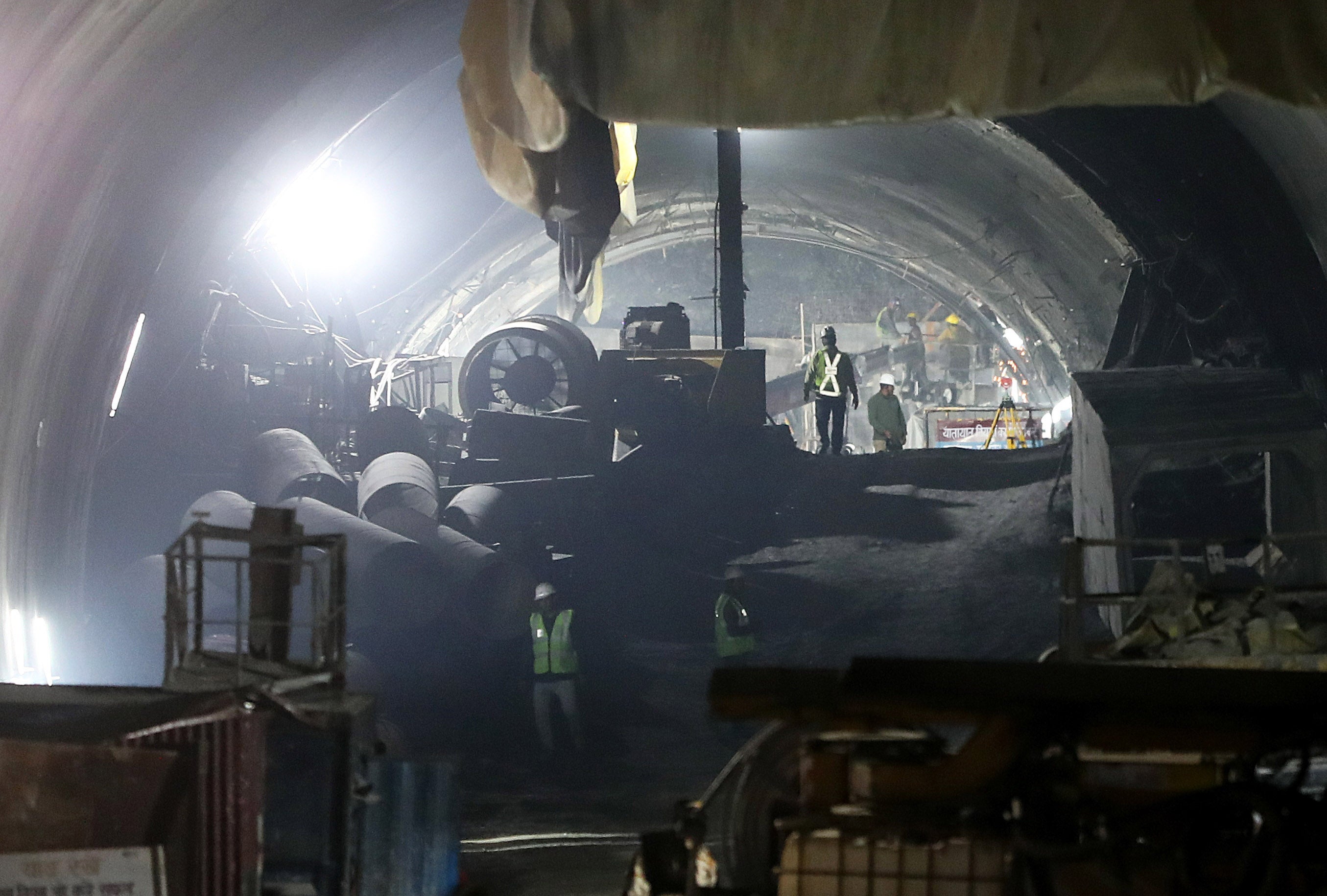 Rescue workers gather among heavy machinery in the tunnel