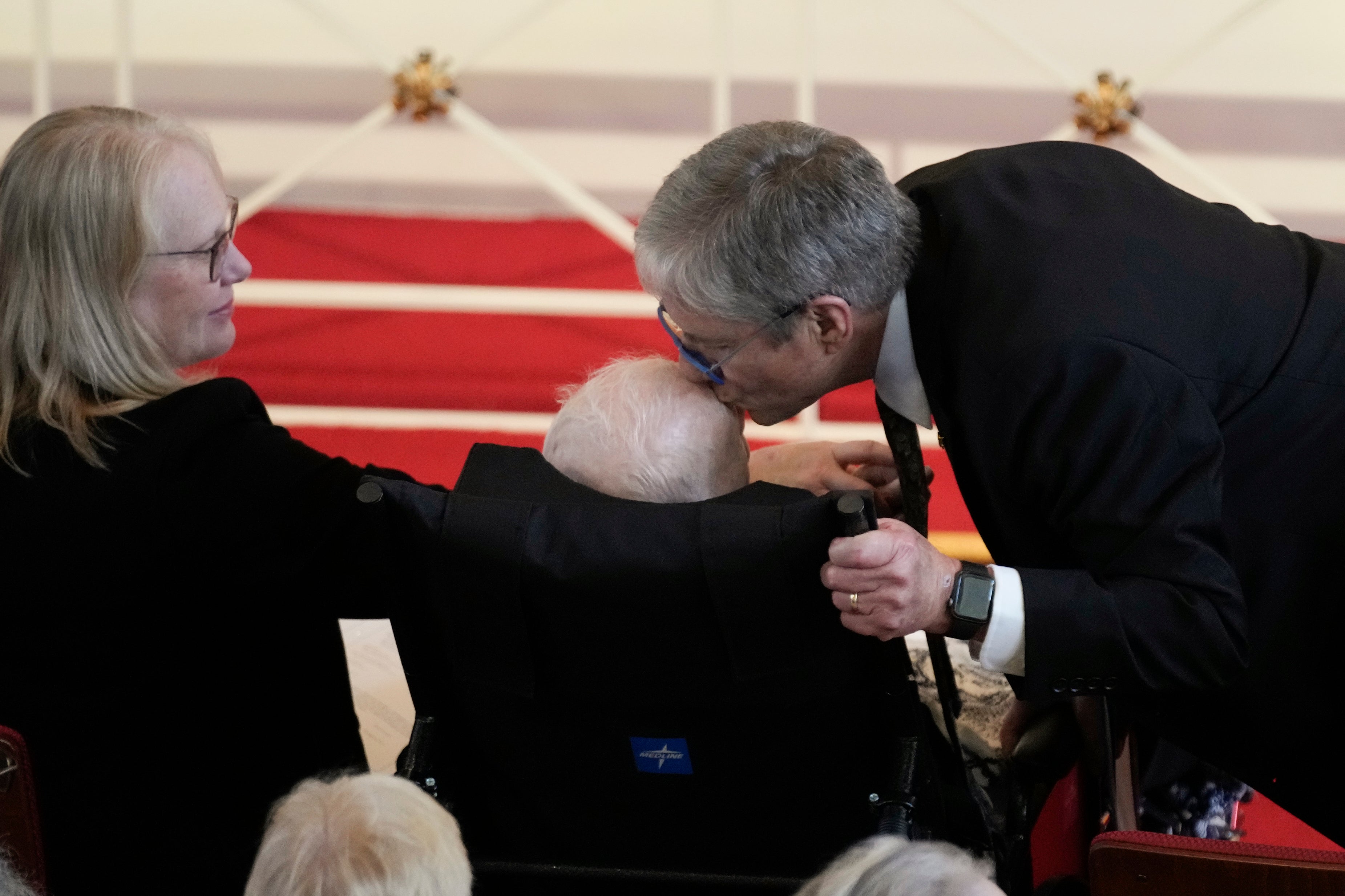 James "Chip" Carter kisses his father, former President Jimmy Carter, after speaking during a tribute service for his mother, former first lady Rosalynn Carter, at Glenn Memorial Church at Emory University on Tuesday, Nov. 28, 2023, in Atlanta, as Amy Carter, left, looks on.