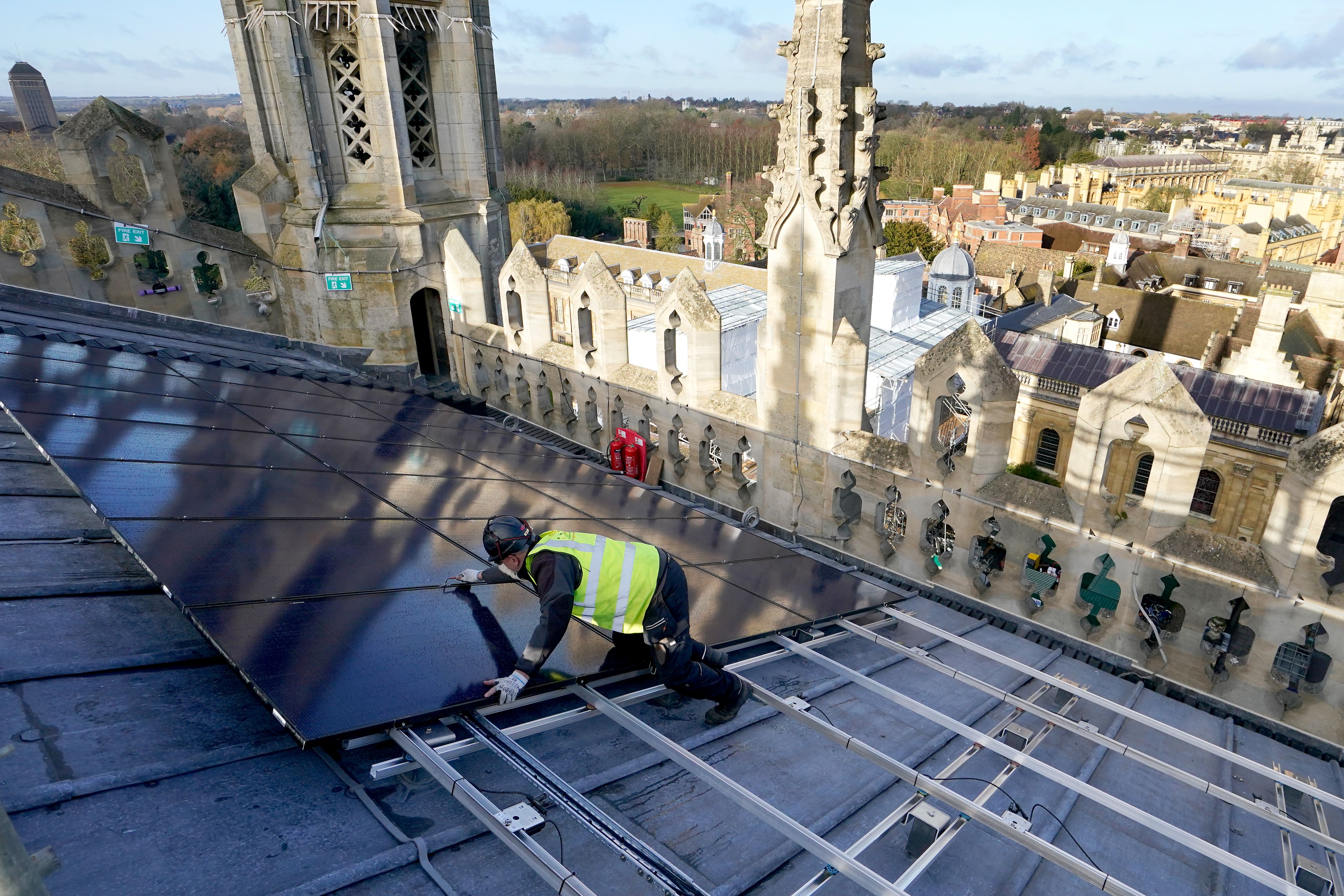 A photovoltaic engineer at work installing solar panels on the roof of the 15th century chapel at King’s College Cambridge (Gareth Fuller/ PA)