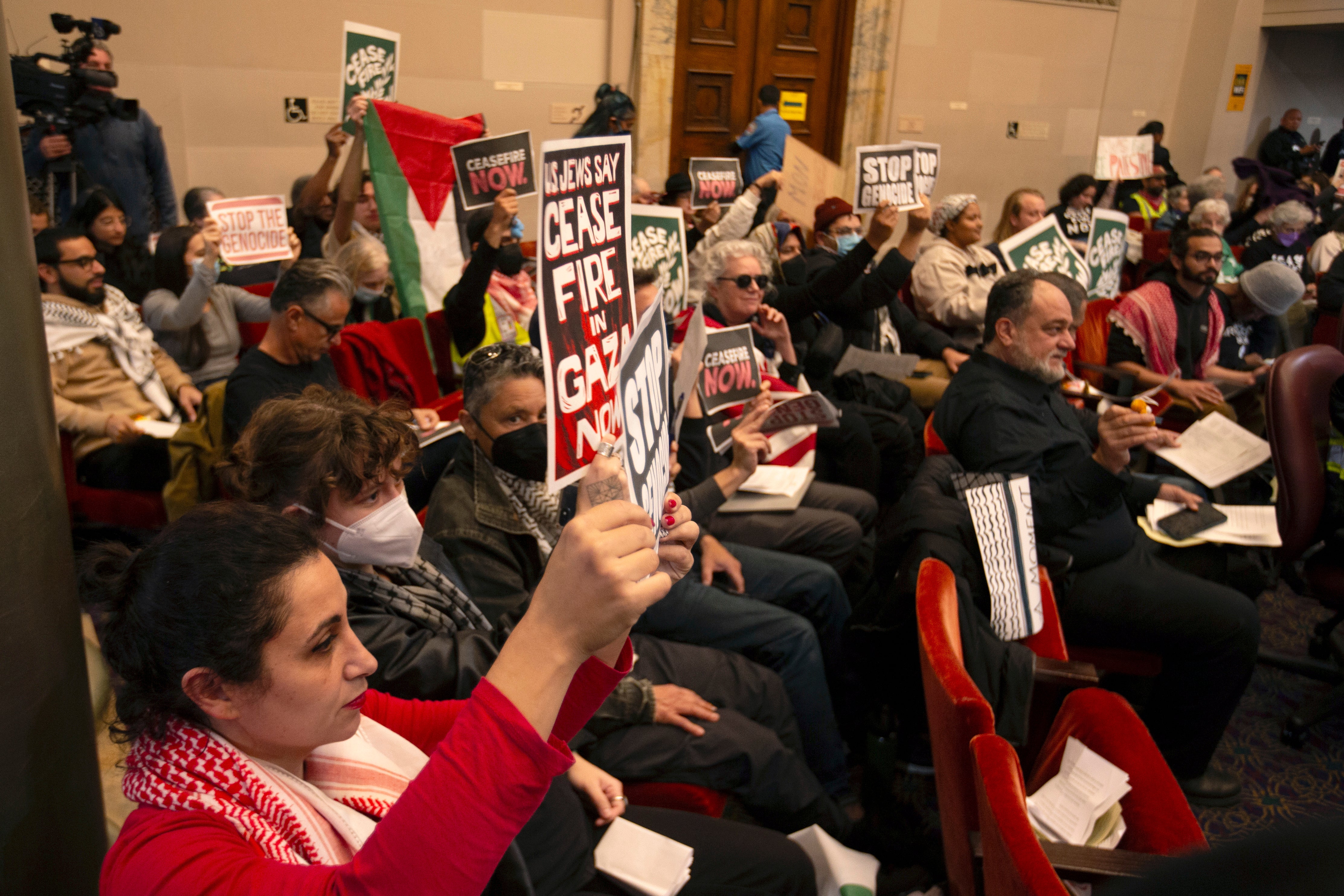 Audience members show their support at a special session of the Oakland City Council for a resolution calling for an immediate cease-fire in Gaza