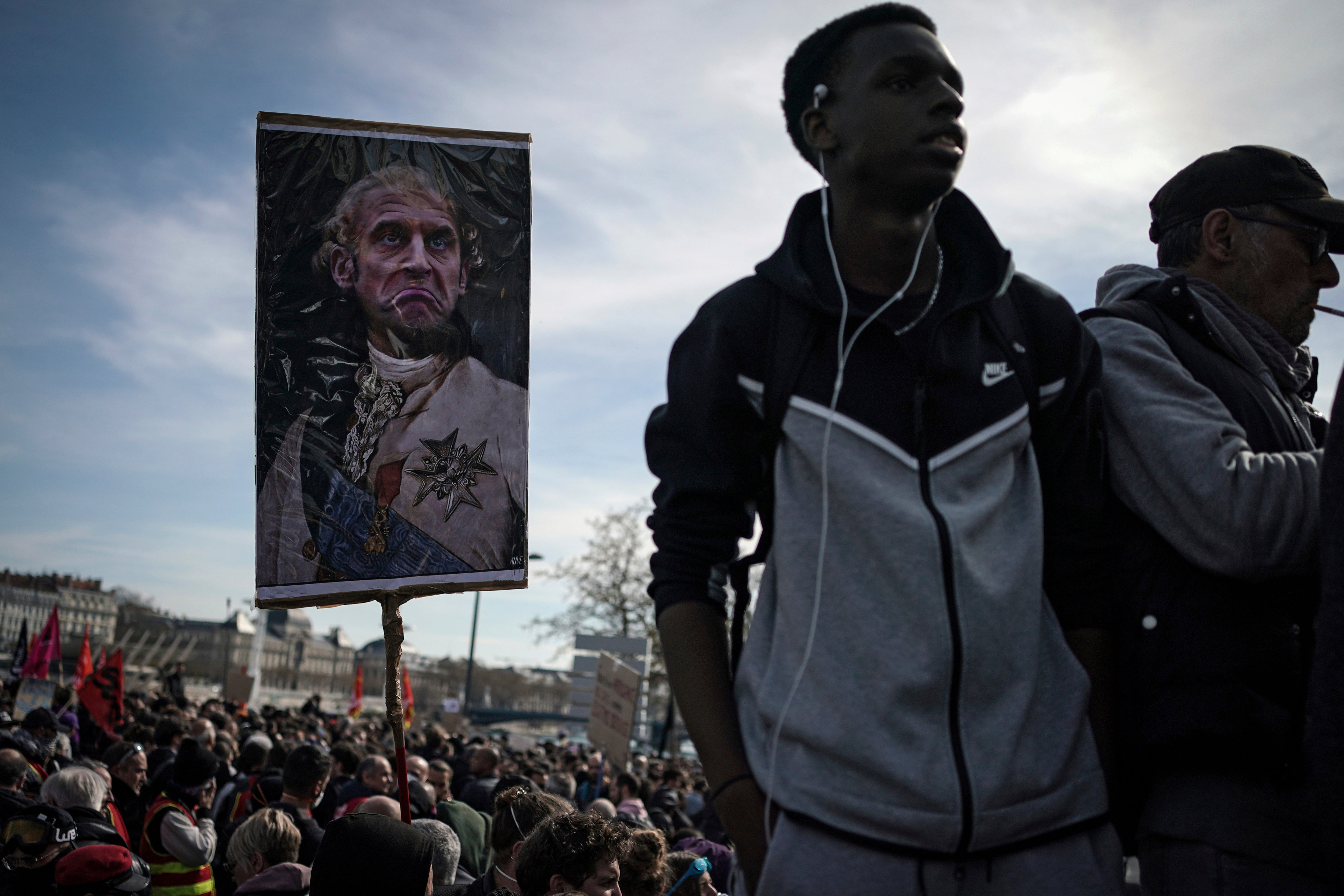 A protester holds a picture representing Emmanuel Macron dressed as a king during a demonstration against unpopular pension reforms in 2023