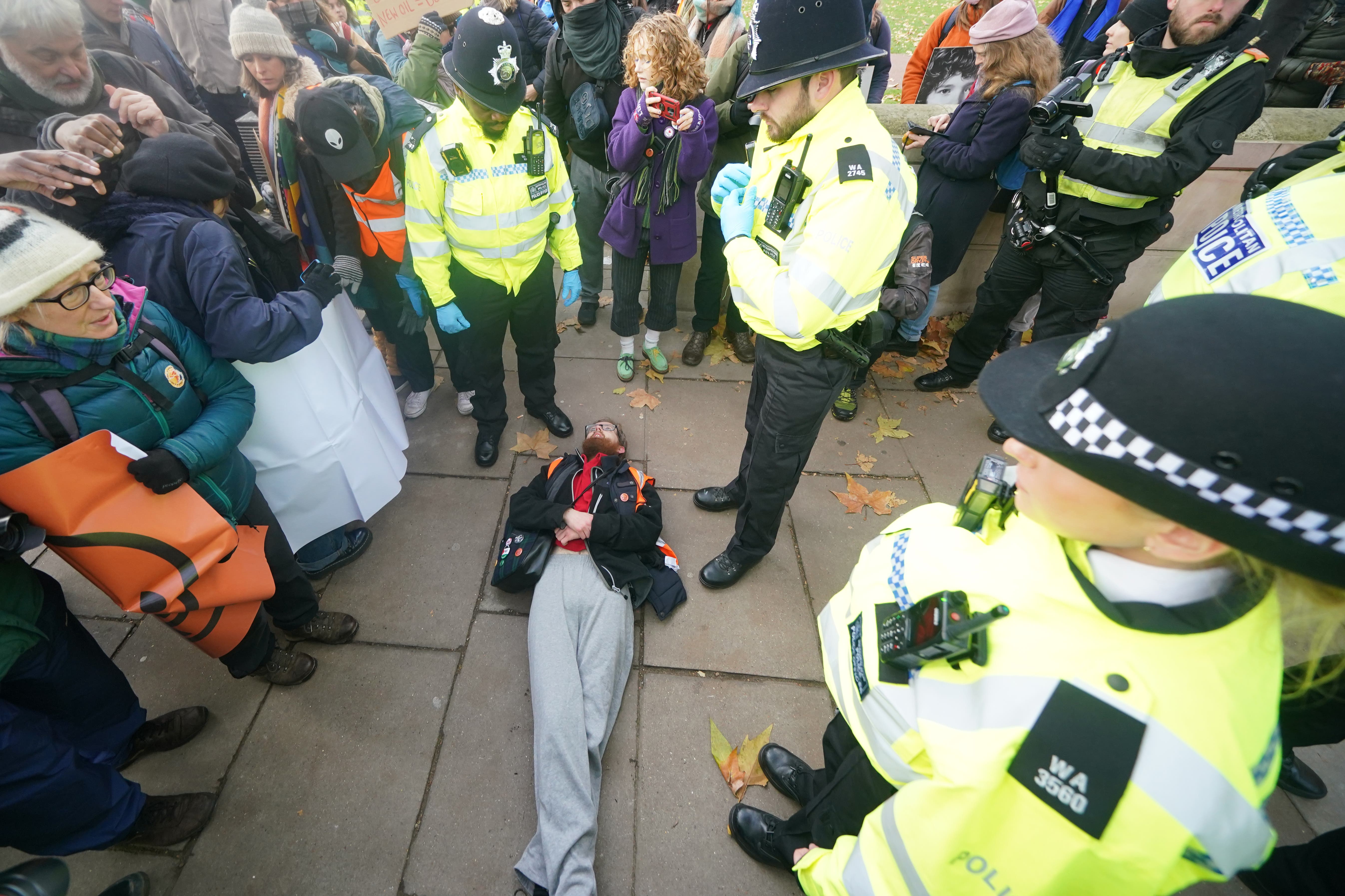 Police officers remove a Just Stop Oil protester outside New Scotland Yard in London on Saturday (Yui Mok/PA)