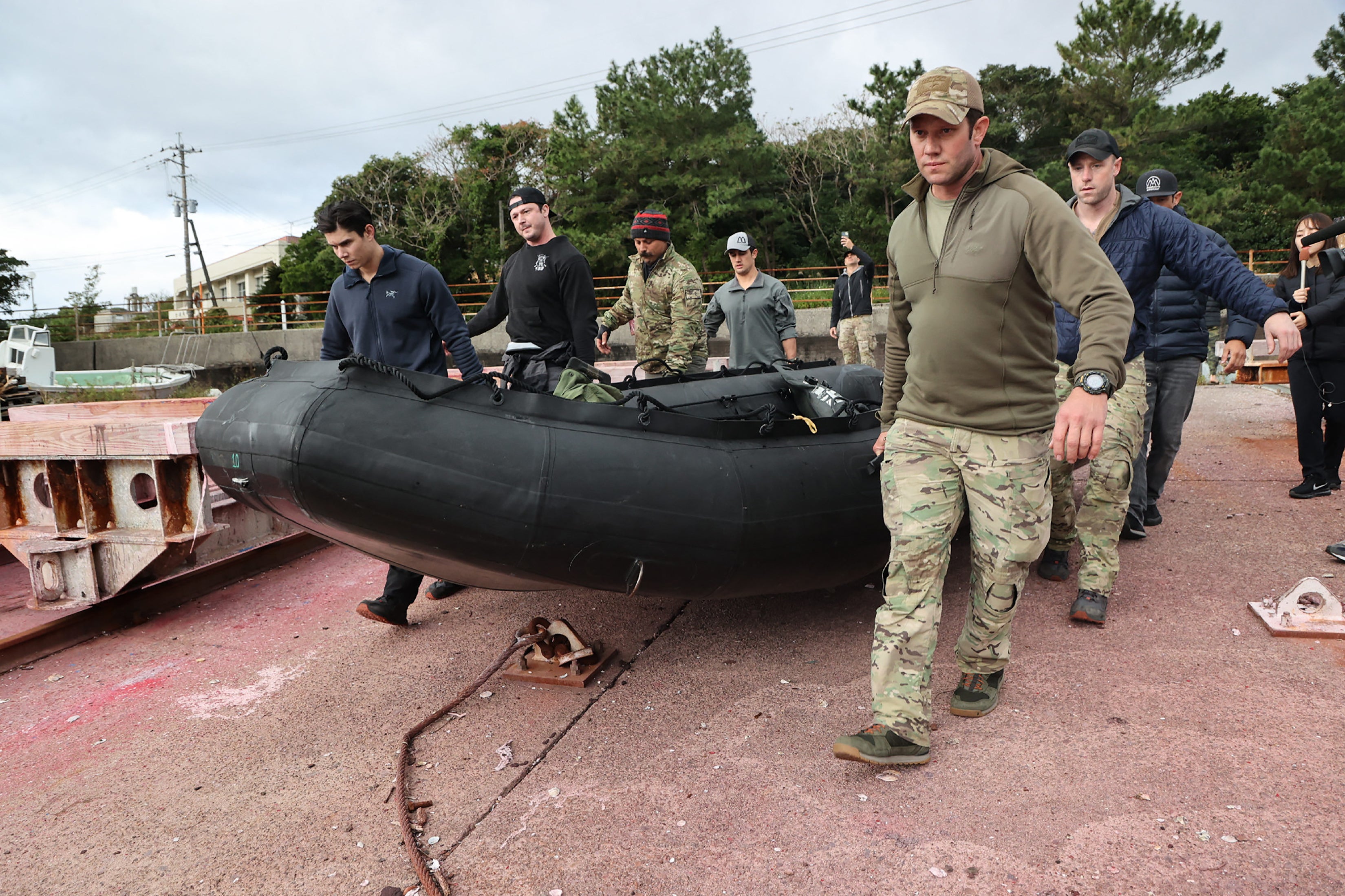 US military personnel carry a dinghy as they head out to search for the crash of a US CV-22B Osprey aircraft, on the island of Yakushima, Kagoshima Prefecture on December 1, 2023