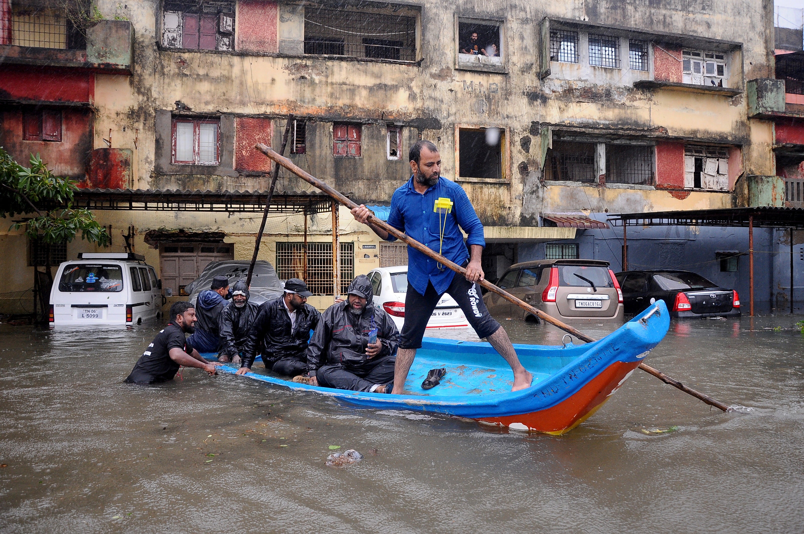 People move in a boat past partially submerged vehicles in Chennai