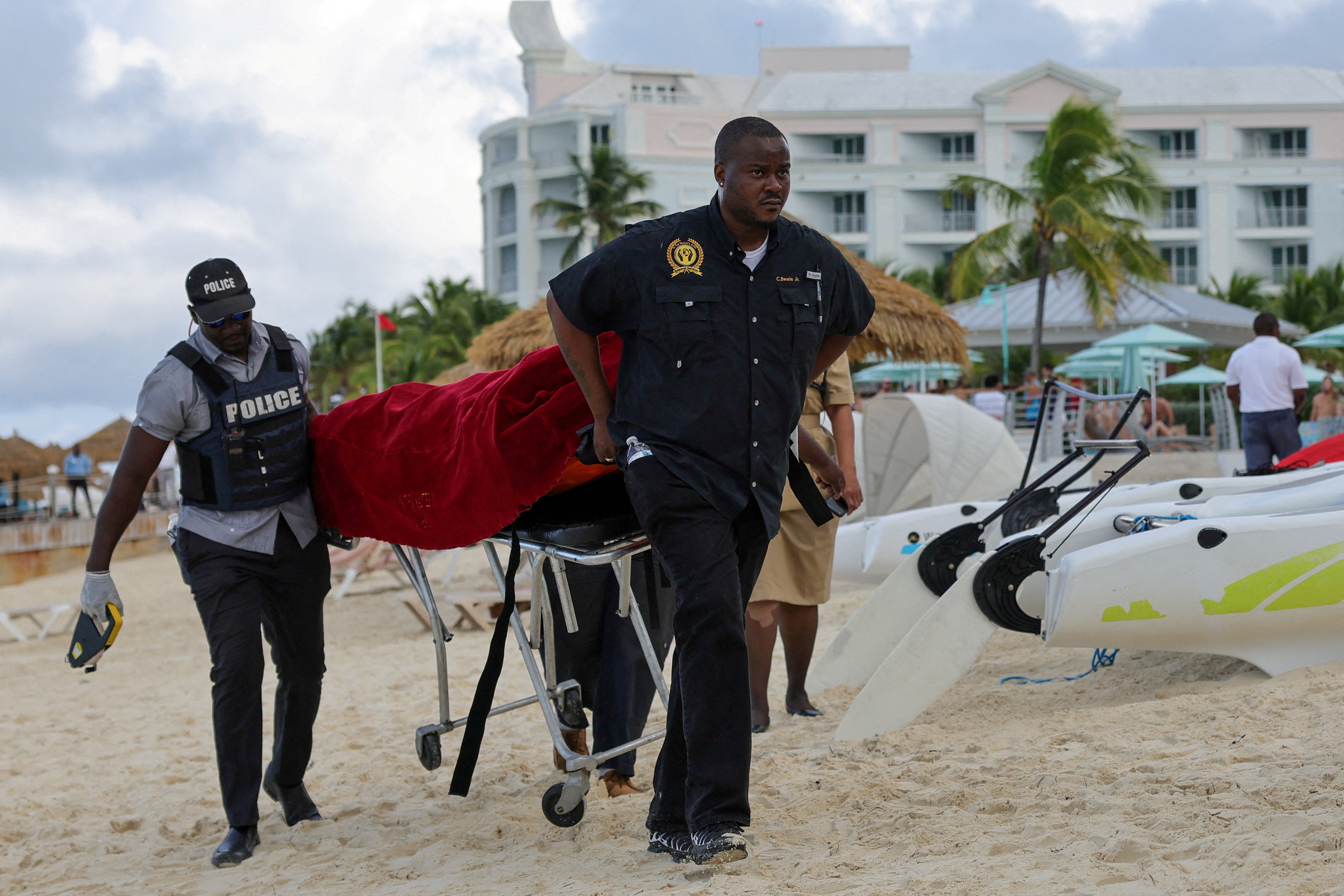 Mortuary services personnel transport the body of a female tourist after what police described as a fatal shark attack in waters near Sandals Royal Bahamian resort, in Nassau, Bahamas