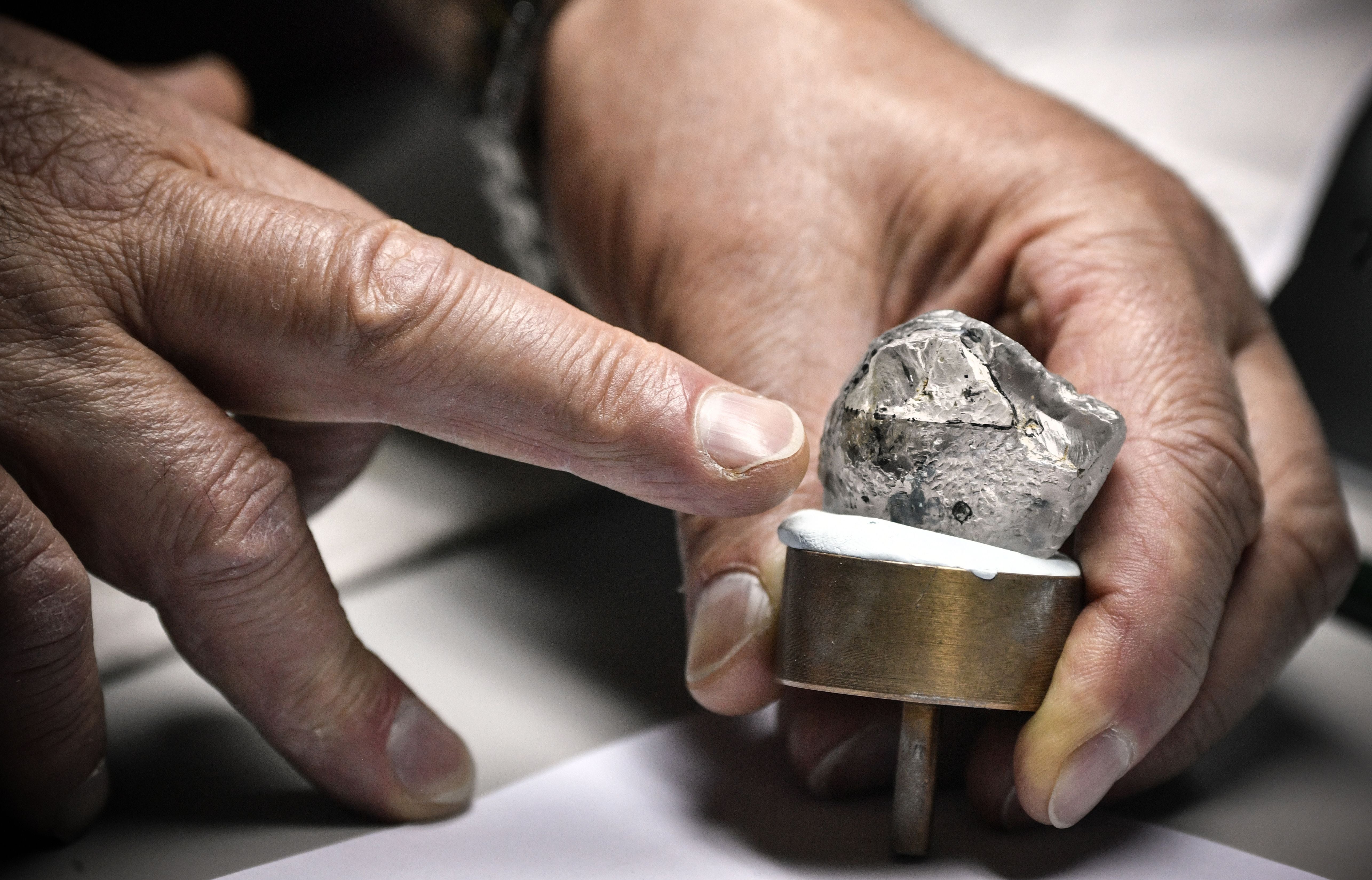 An employee inspects rough diamonds at Alrosa Diamond Cutting Division in Moscow