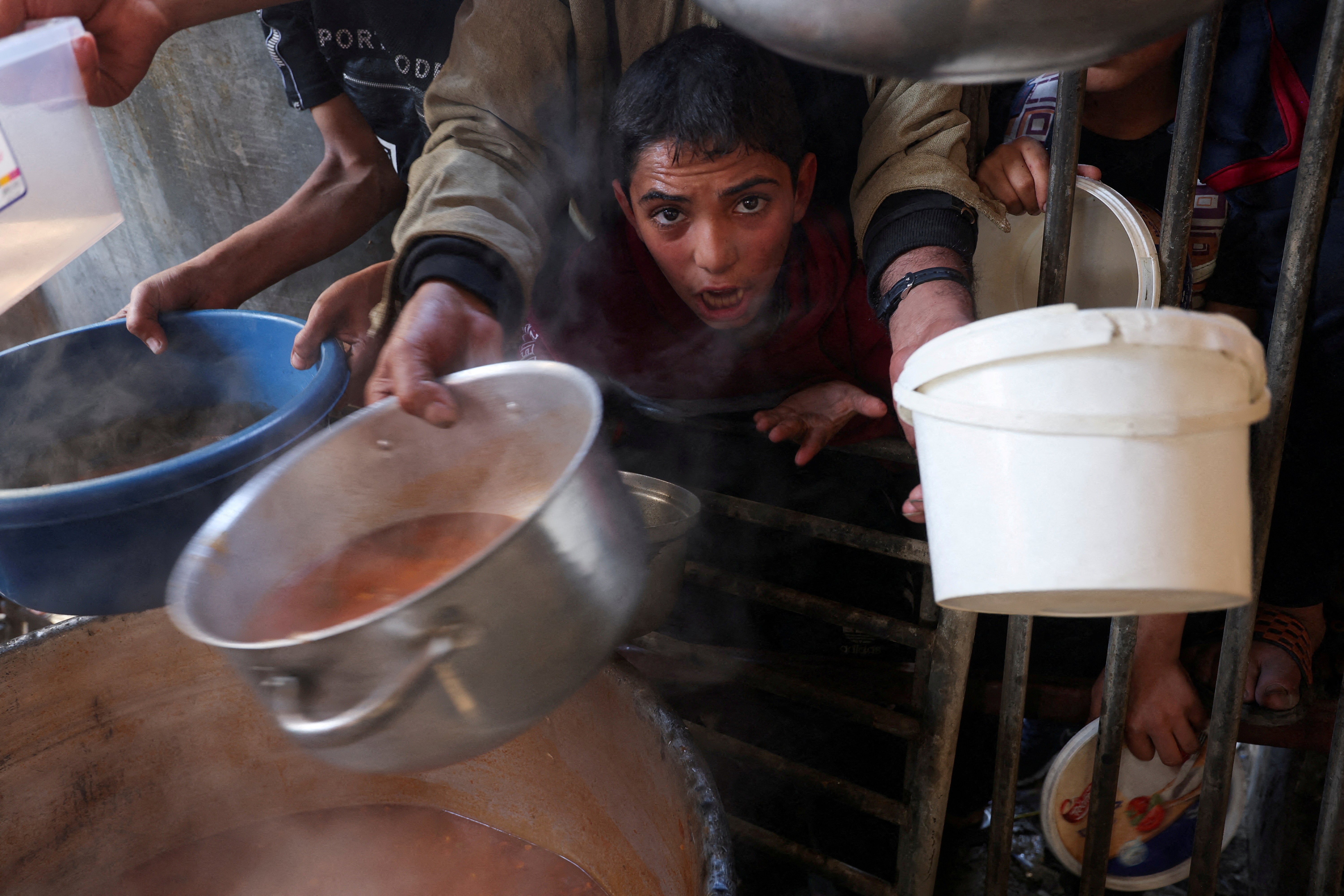 Gaza residents gather to get their share of food offered by aid group volunteers in Rafah