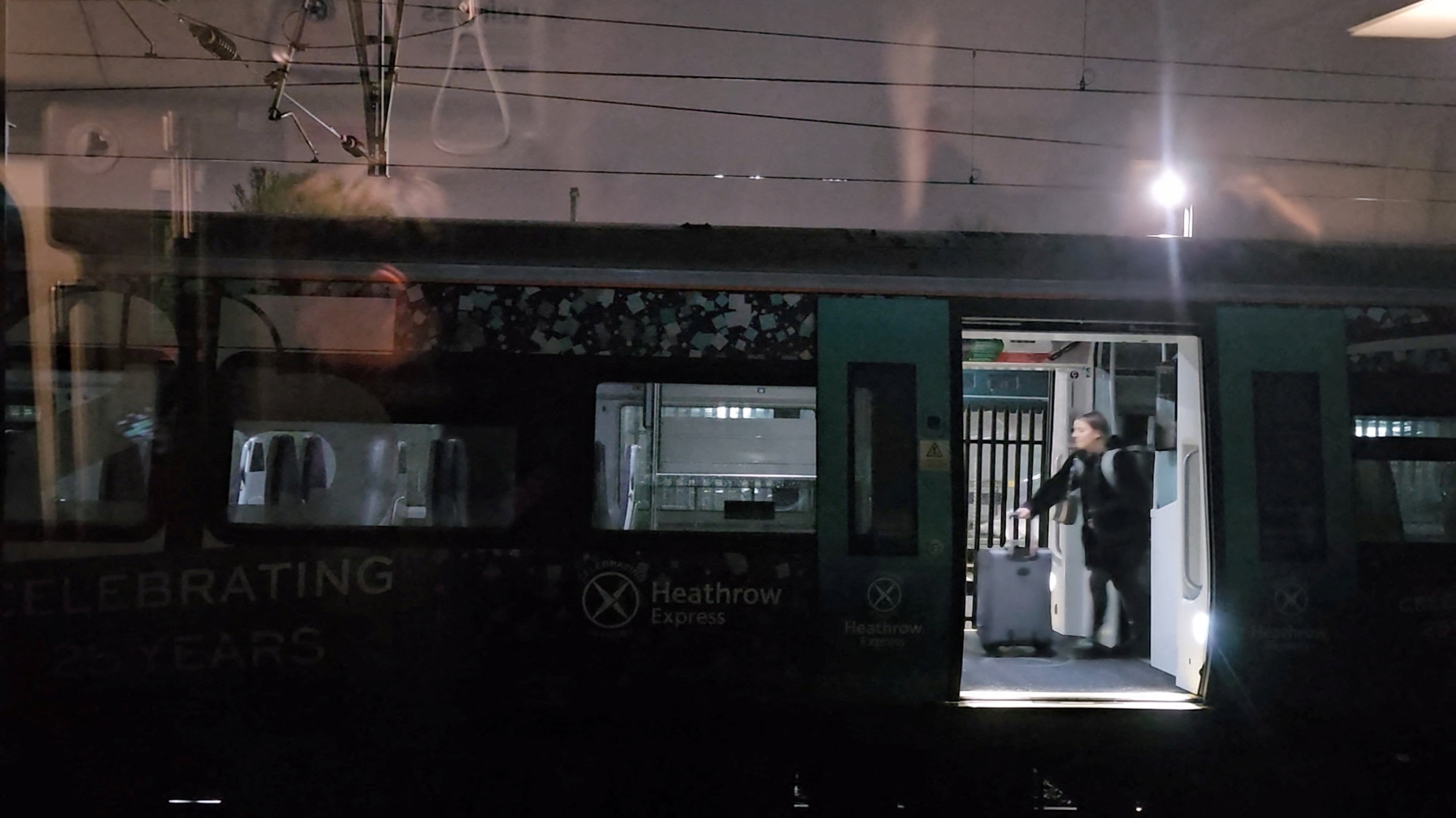 A passenger walks with luggage inside the Heathrow Express train stuck on the Elizabeth Line