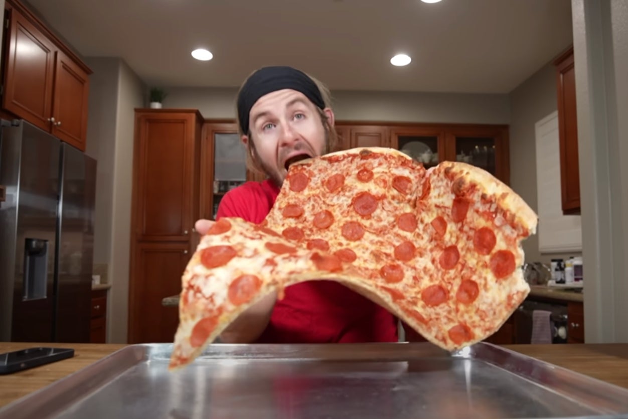 Fitness influencer Erik Lamkin munches into a giant slice of pizza on his YouTube channel