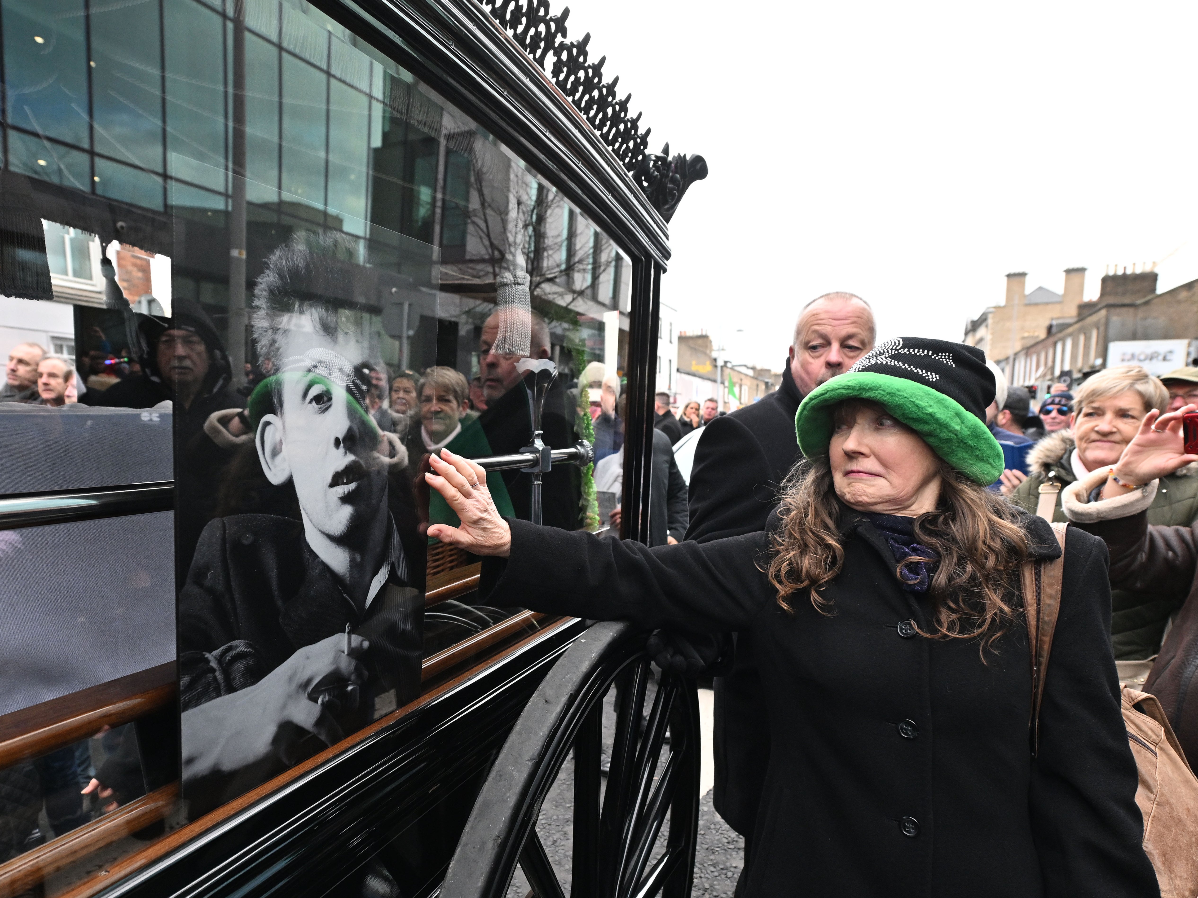 Fans touch the glass window of the carriage during the funeral procession