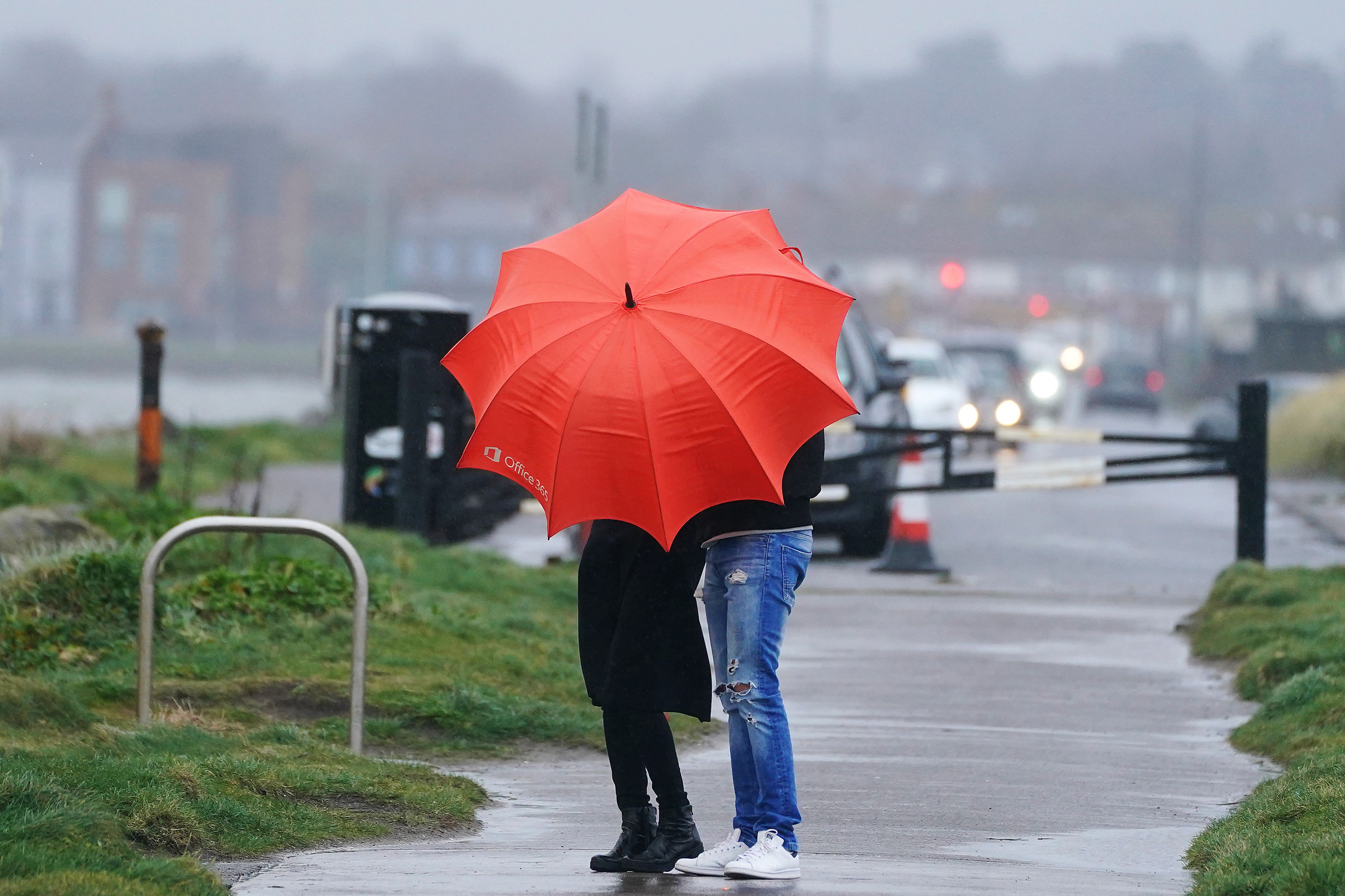 People go for a walk on the Bull Wall on a wet and windy day in Dublin (Brian Lawless/PA)