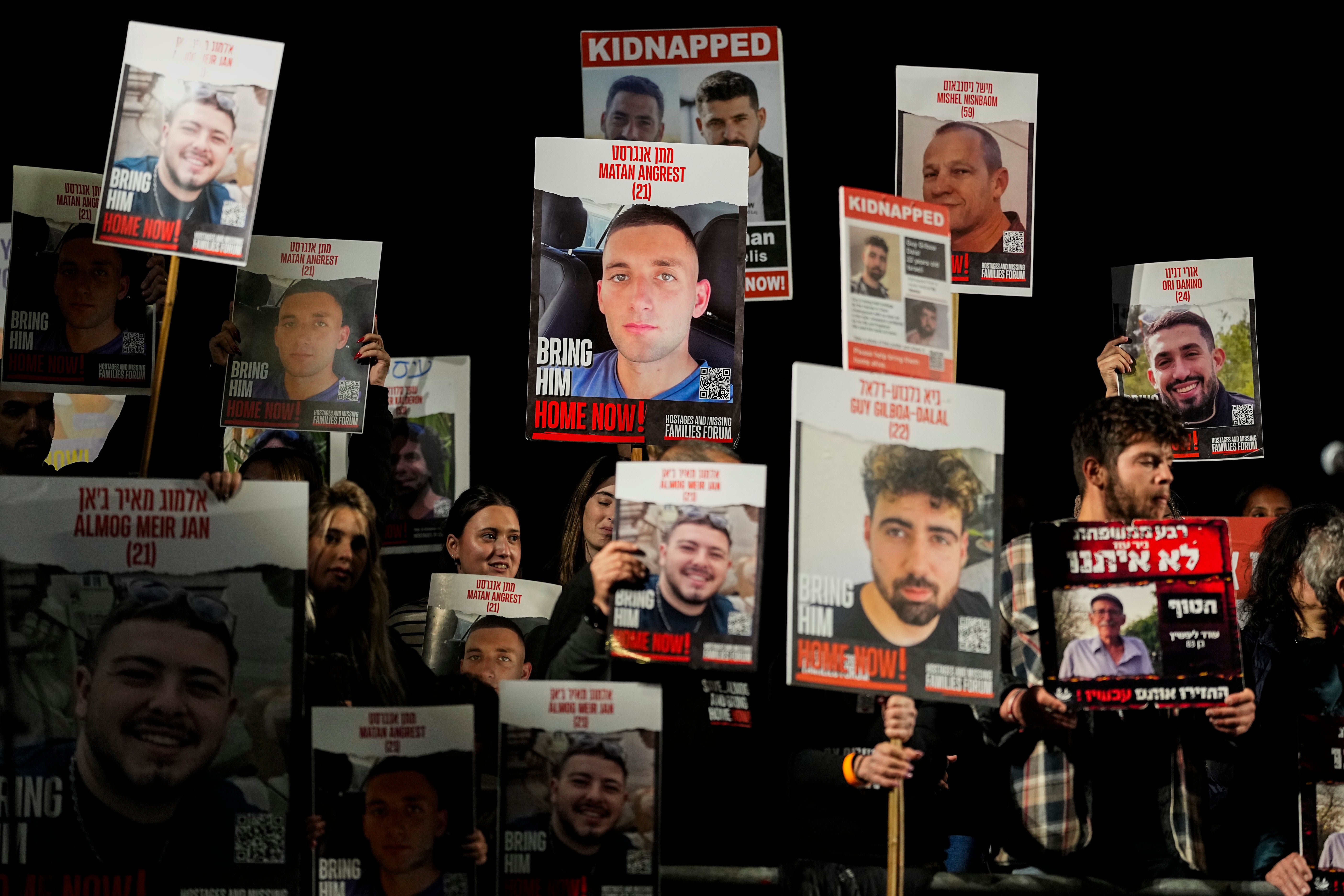 People hold pictures in Tel Aviv last night of Israeli hostages held by Hamas