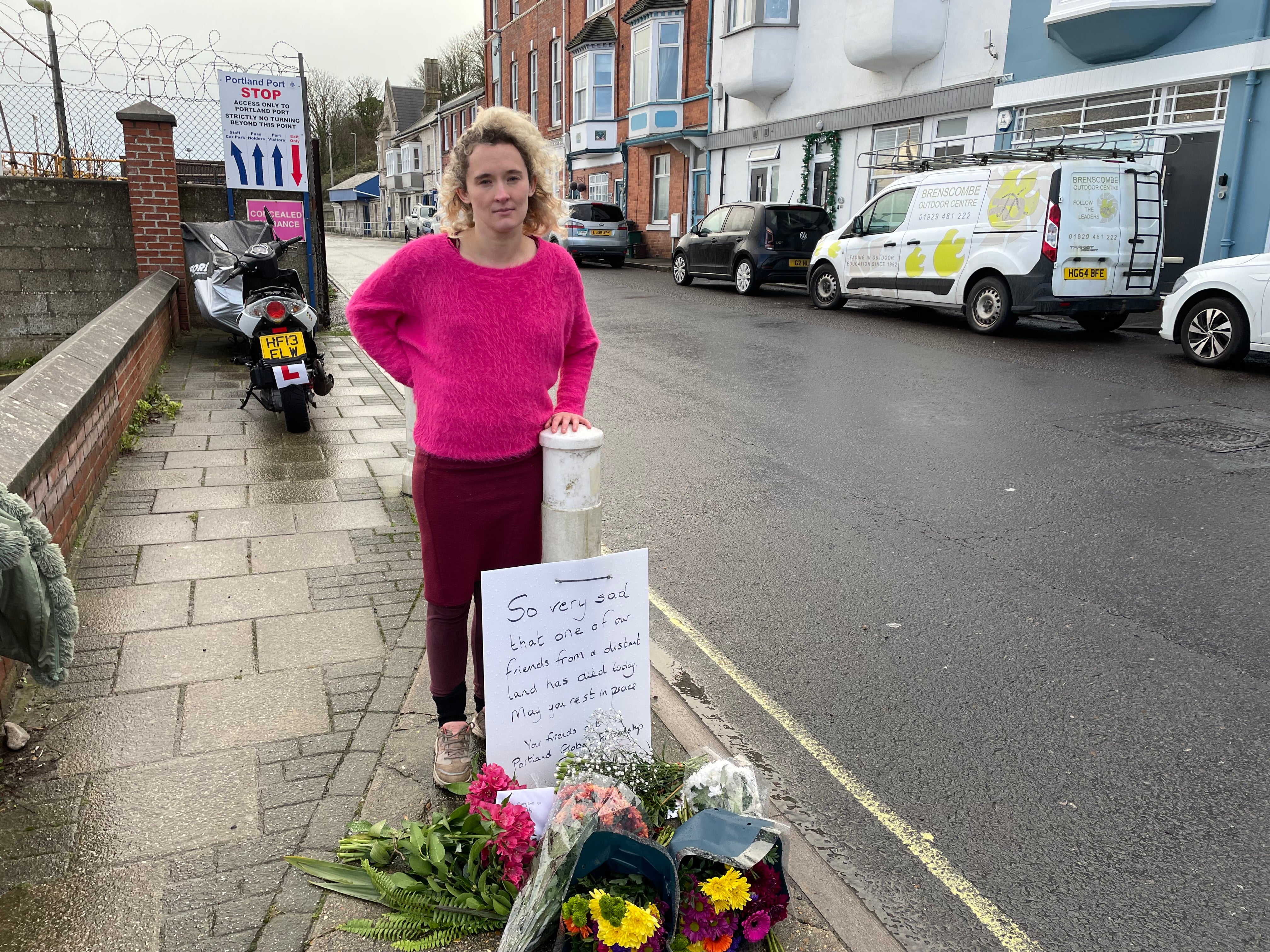 Heather, from the Portland Global Friendship Group, next to flowers laid in memory of the man who died on the Bibby Stockholm vessel