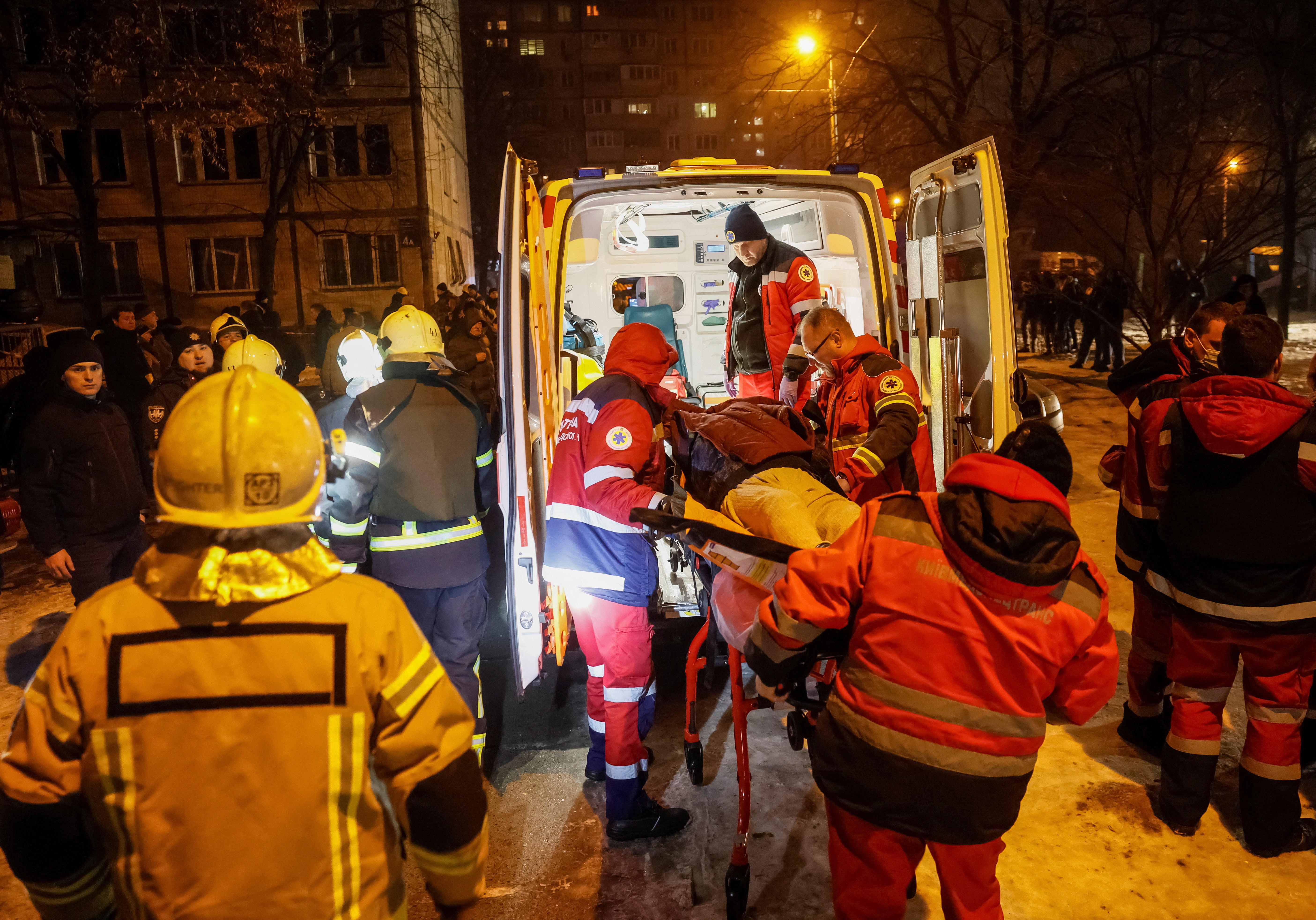 Medics carry a wounded local resident at a site of an apartment building damaged during a Russian missile strike in Kyiv