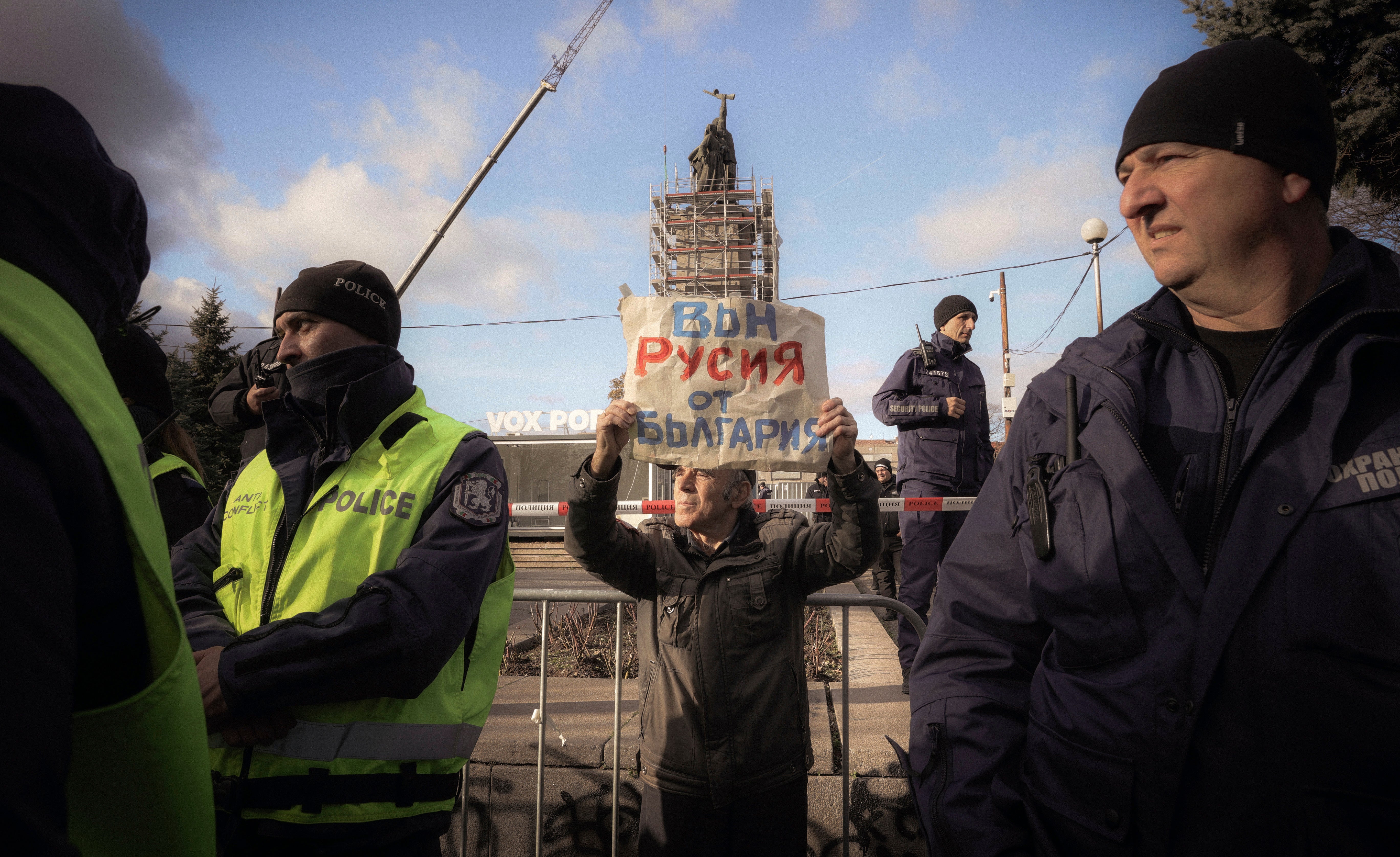 A protester holds a placard reading “Russia out of Bulgaria” demonstrates surrounded by policemen