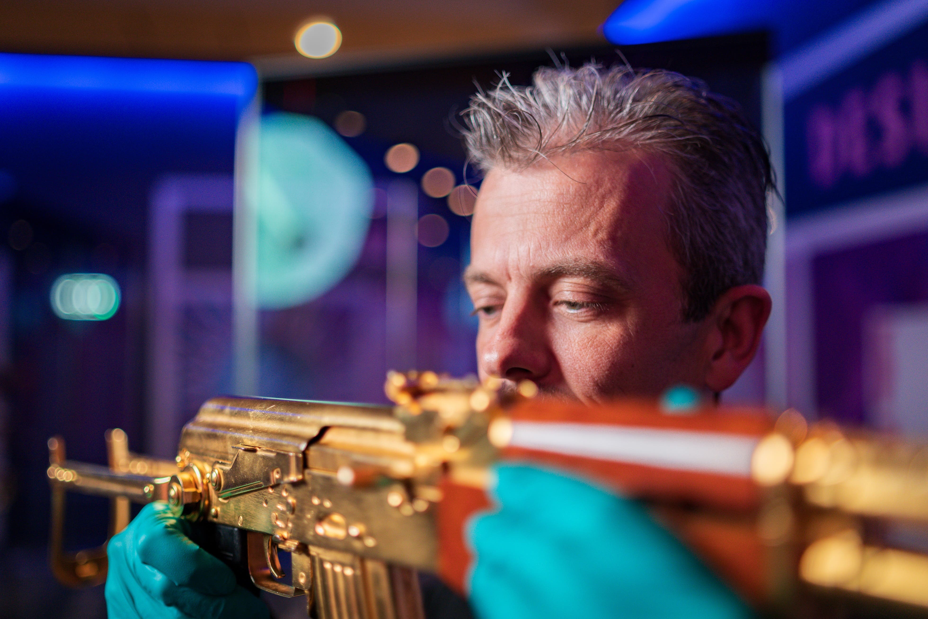 Curator Jonathan Ferguson with gold AK47 at Reloaded exhibition Royal Armouries Leeds (Royal Armouries/PA)