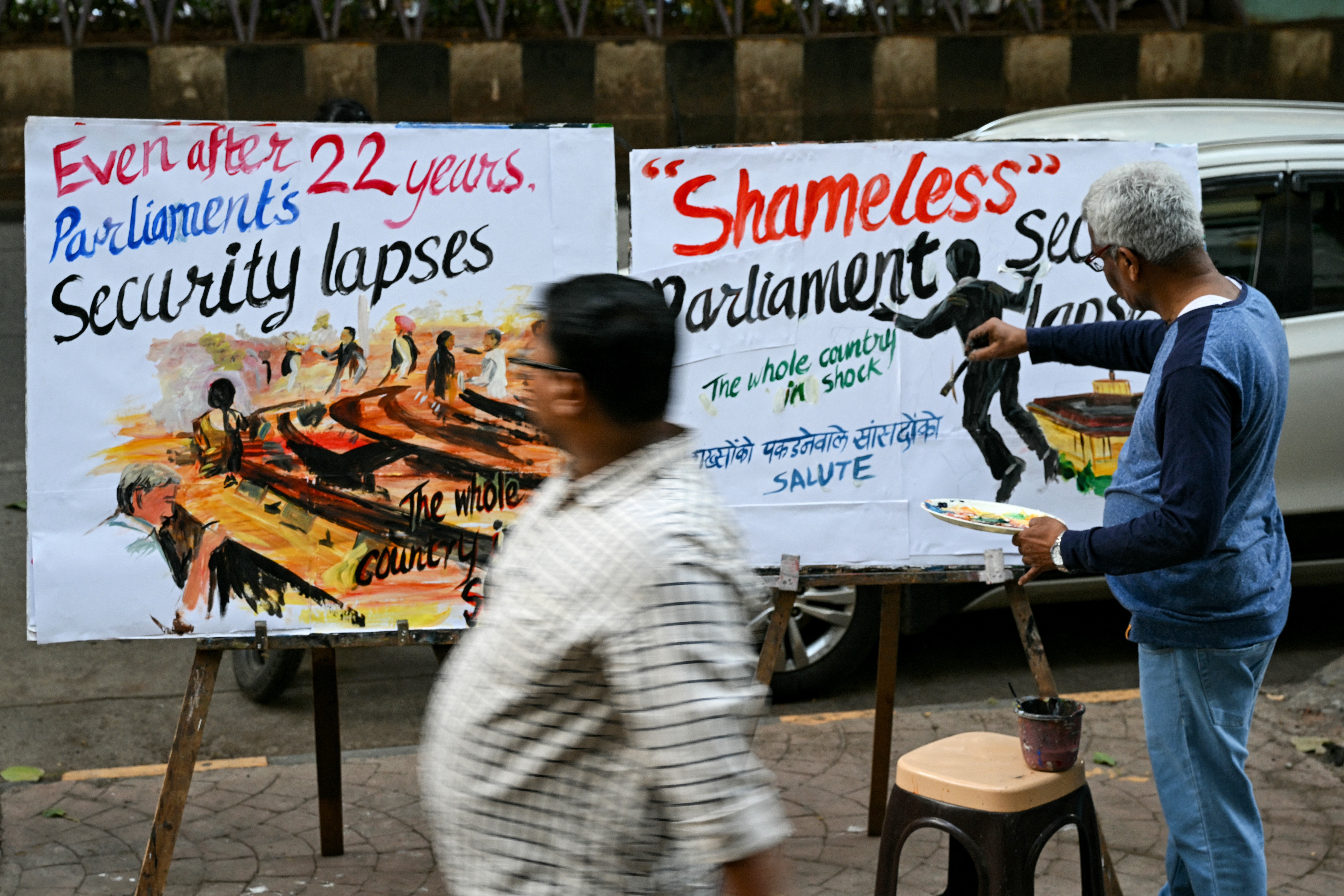 An art school teacher works on a painting along a pavement in Mumbai depicting the security breach inside the lower house Lok Sabh