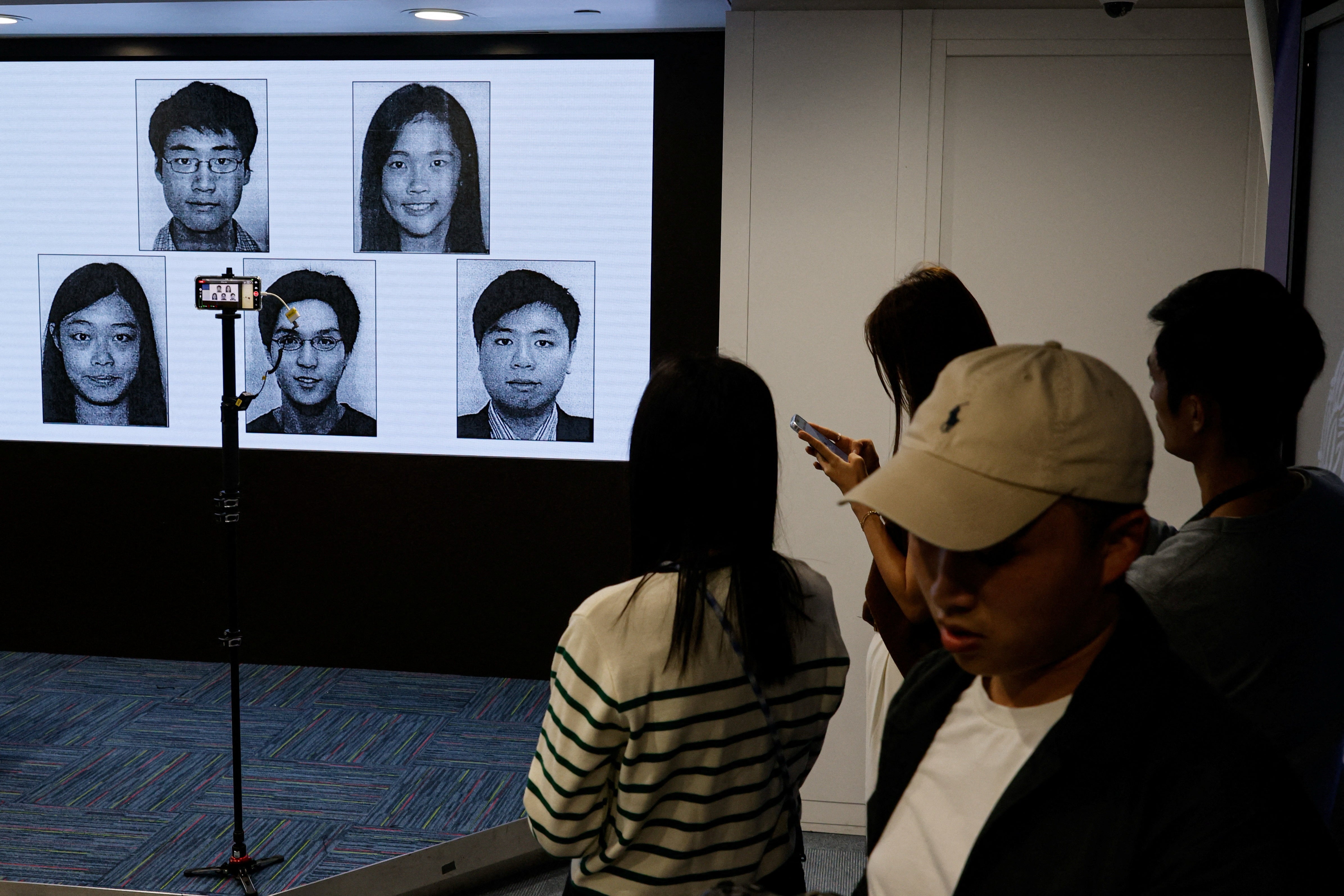 Images of five activists Simon Cheng, Frances Hui, Joey Siu, Johnny Fok, and Tony Choi are displayed during a press conference to issue arrest warrants in Hong Kong