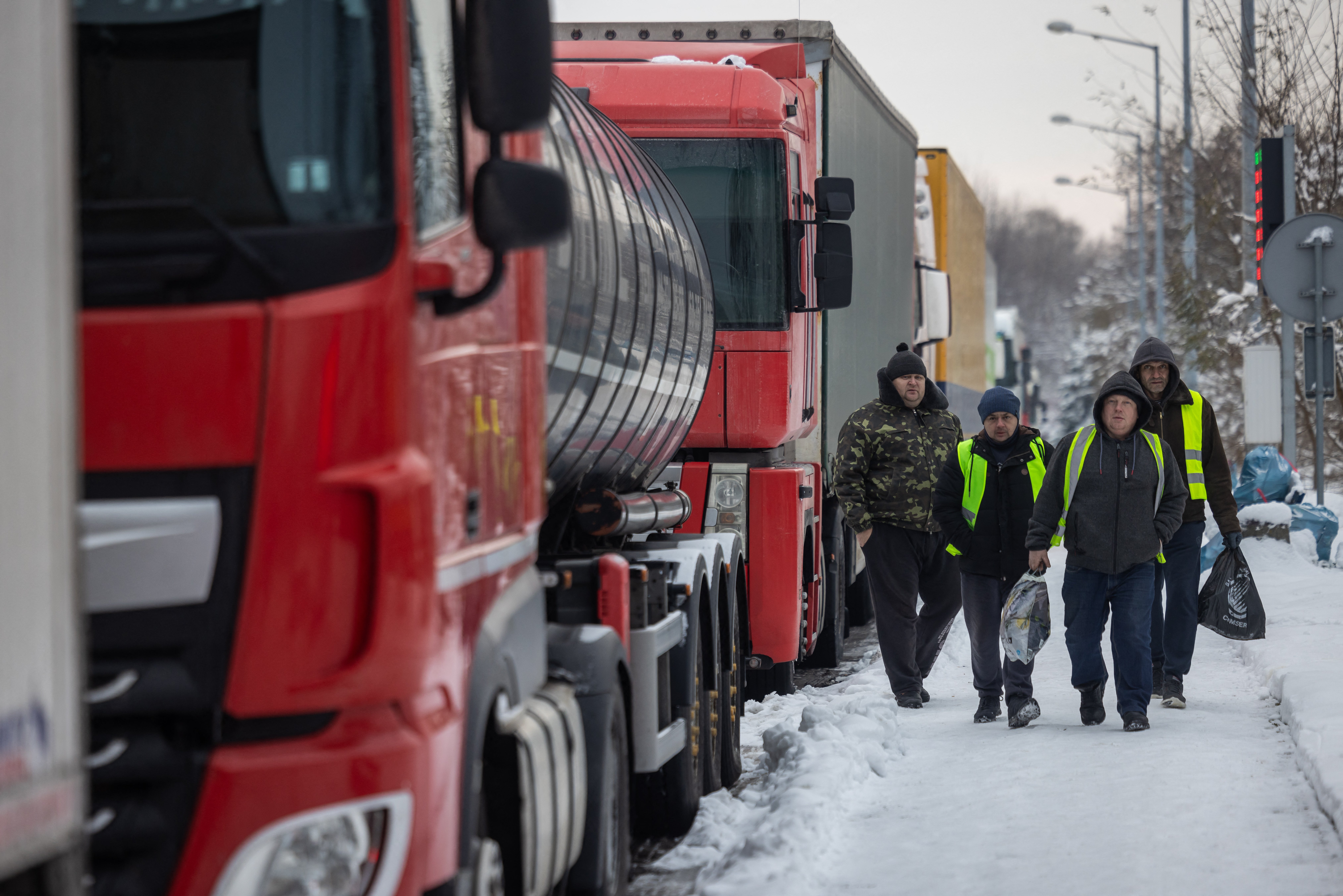 Ukrainian truck drivers walks past Ukrainian trucks as they carry bags full of groceries, on the parking lot near Korczowa Polish-Ukrainian border crossing