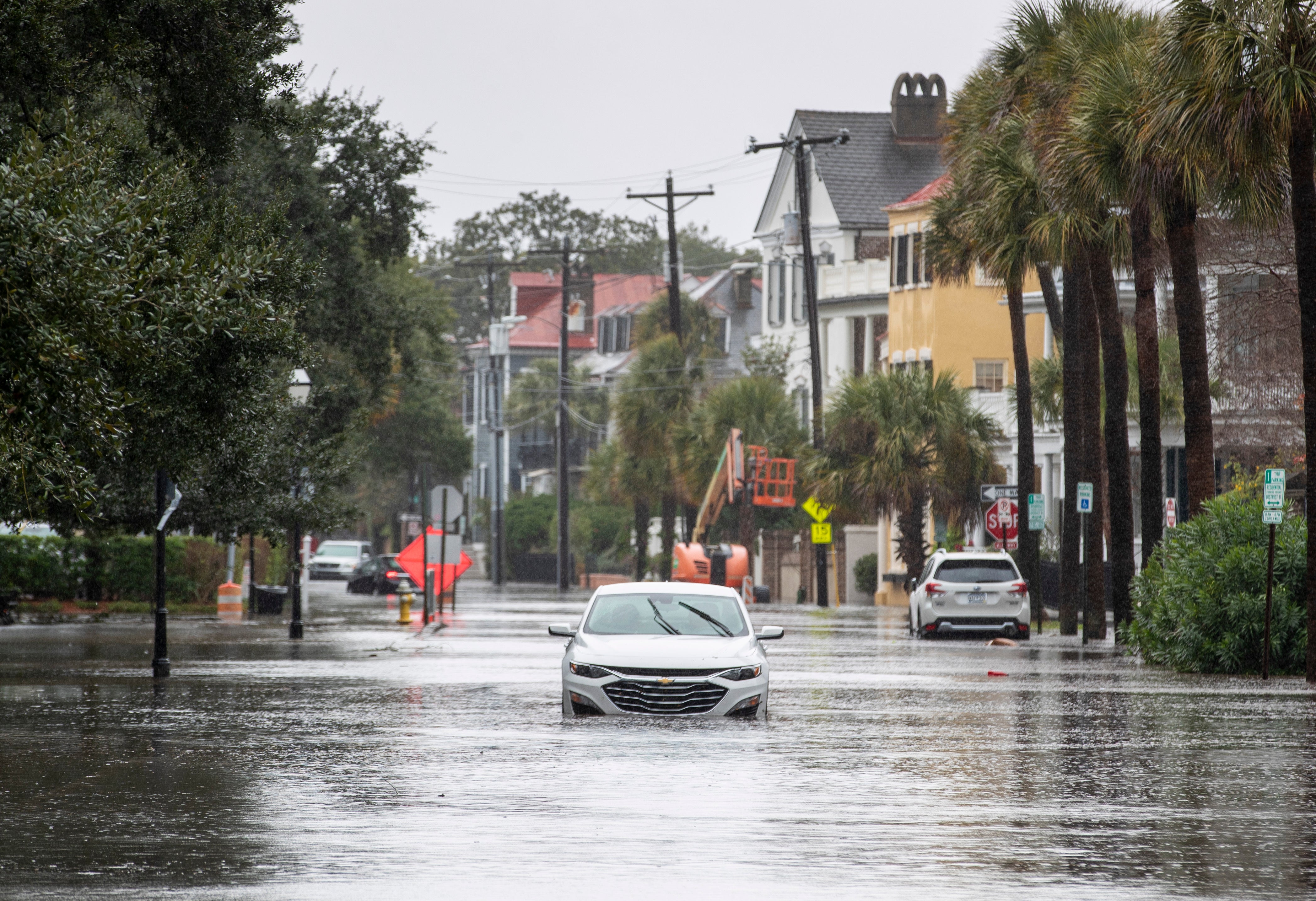 A car drives through a flooded street near the Battery, Sunday